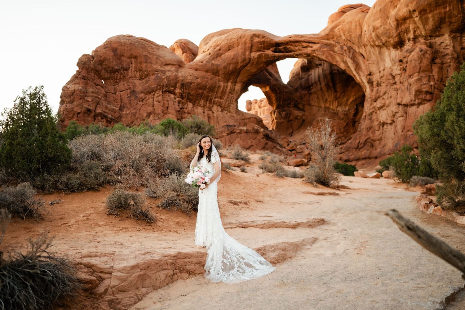 A wedding ceremony set against stunning red rock arches in a desert landscape.