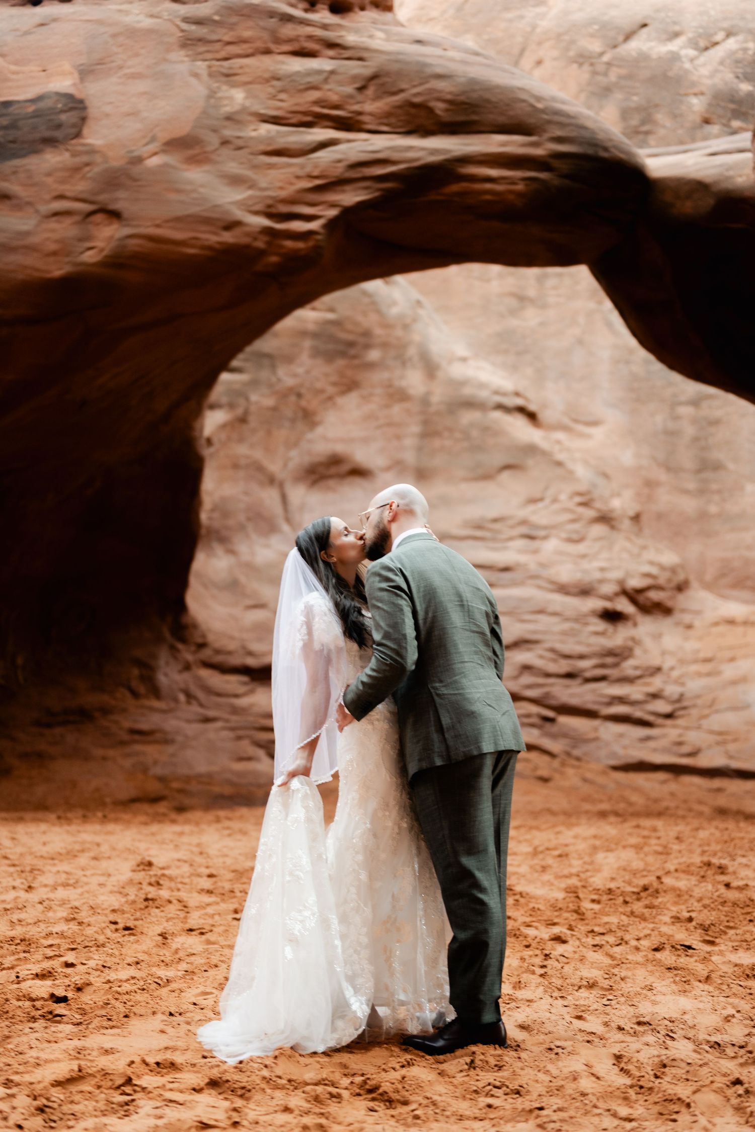 A romantic wedding scene beneath a natural desert rock arch formation.