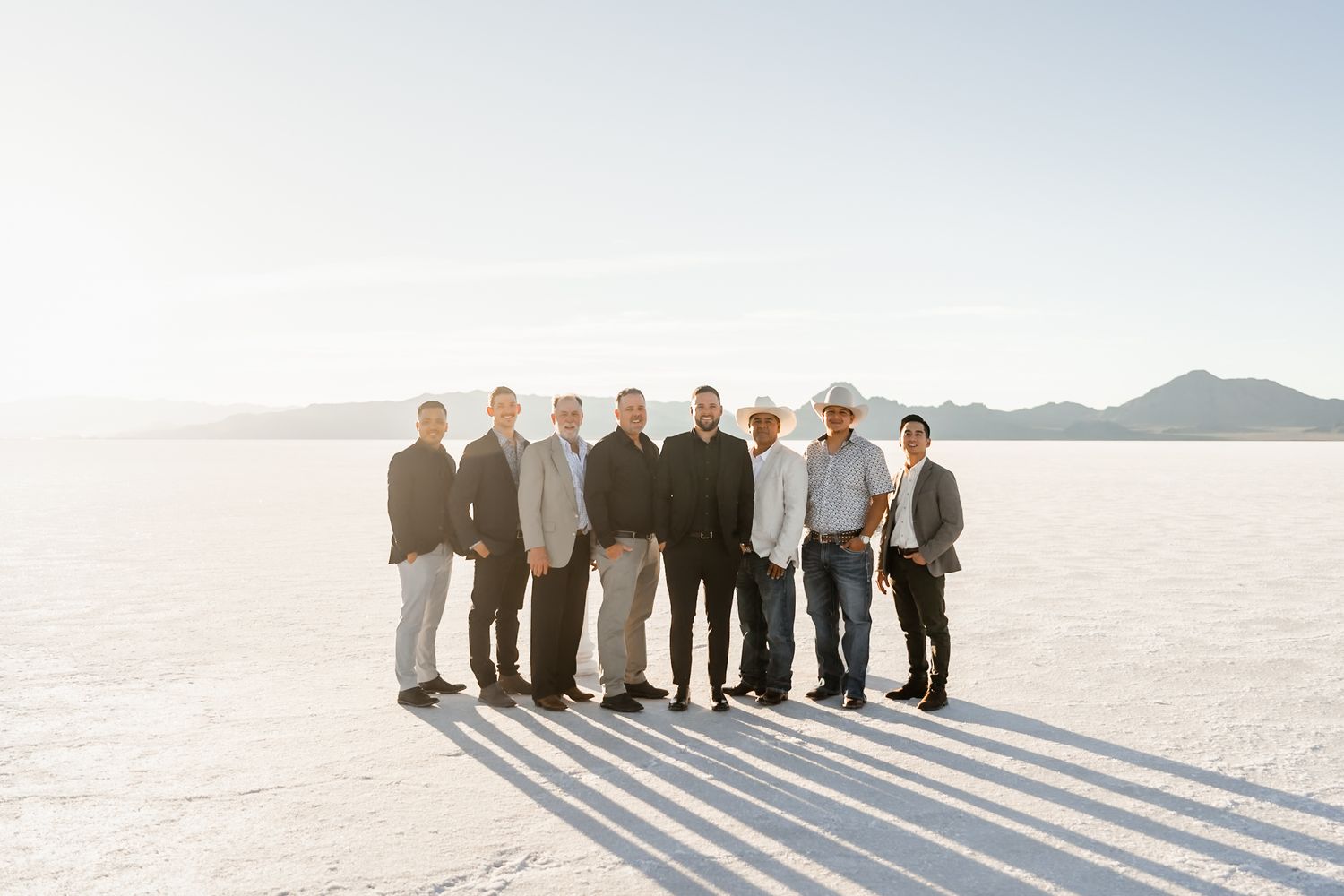 Wedding group photo with dramatic shadows on white salt flats landscape.
