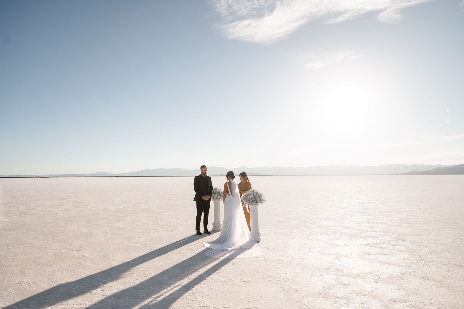 Elegant wedding ceremony on salt flats with long shadows and mountain backdrop.