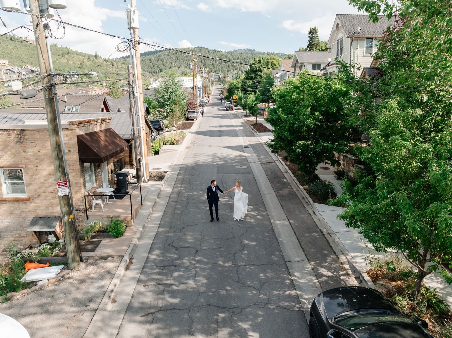 Narrow residential street with stone buildings and utility poles winding up a steep hill in a Mediterranean town.
