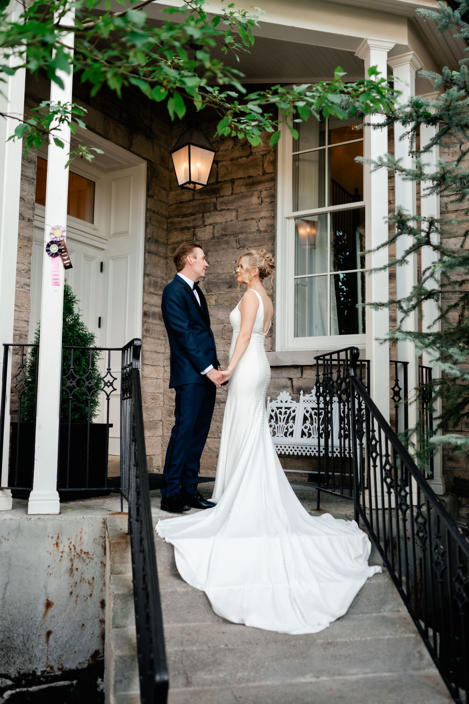 Couple dancing on stone steps with white columns and greenery in background.