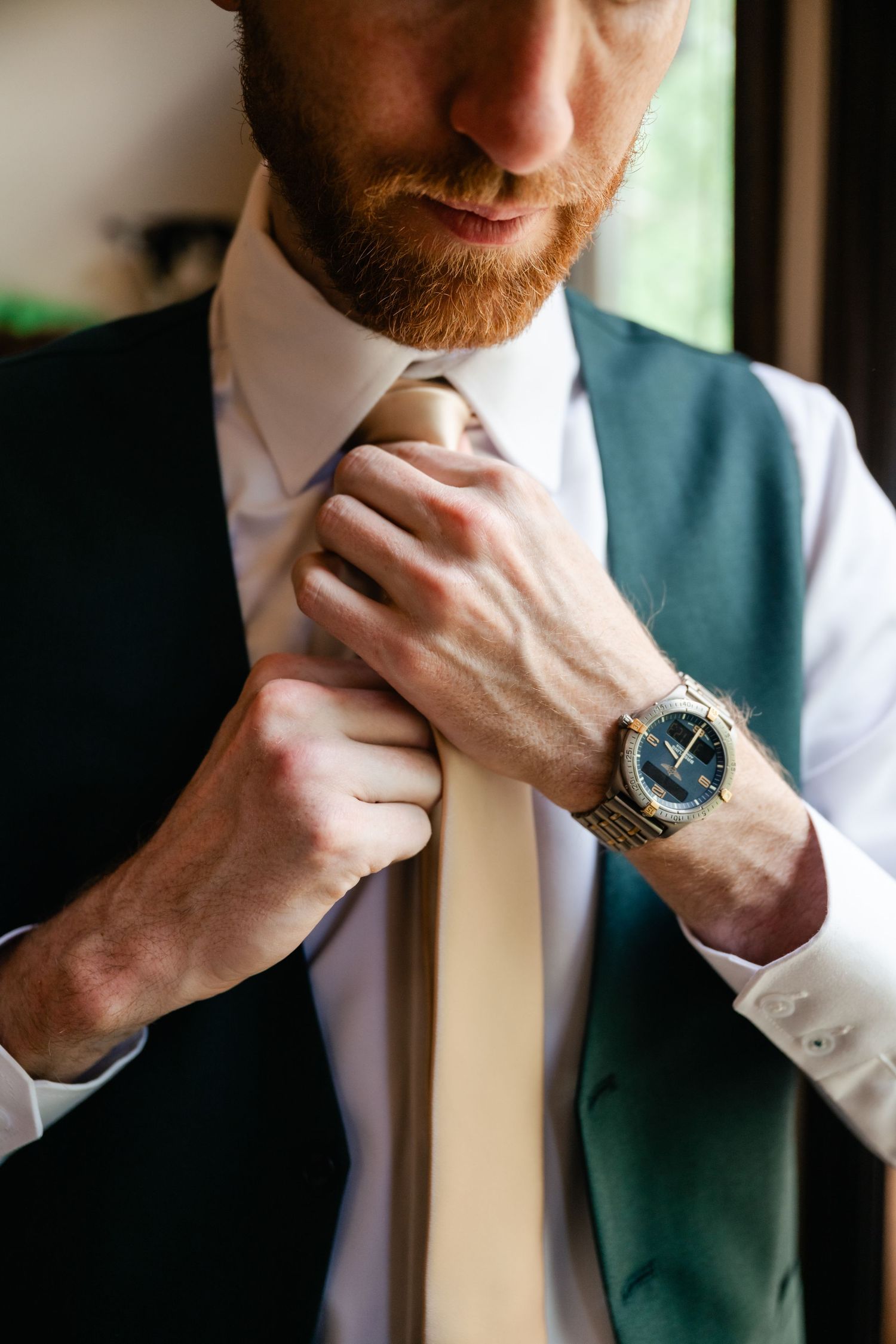 Close-up shot of hands adjusting collar while wearing formal vest and white shirt.