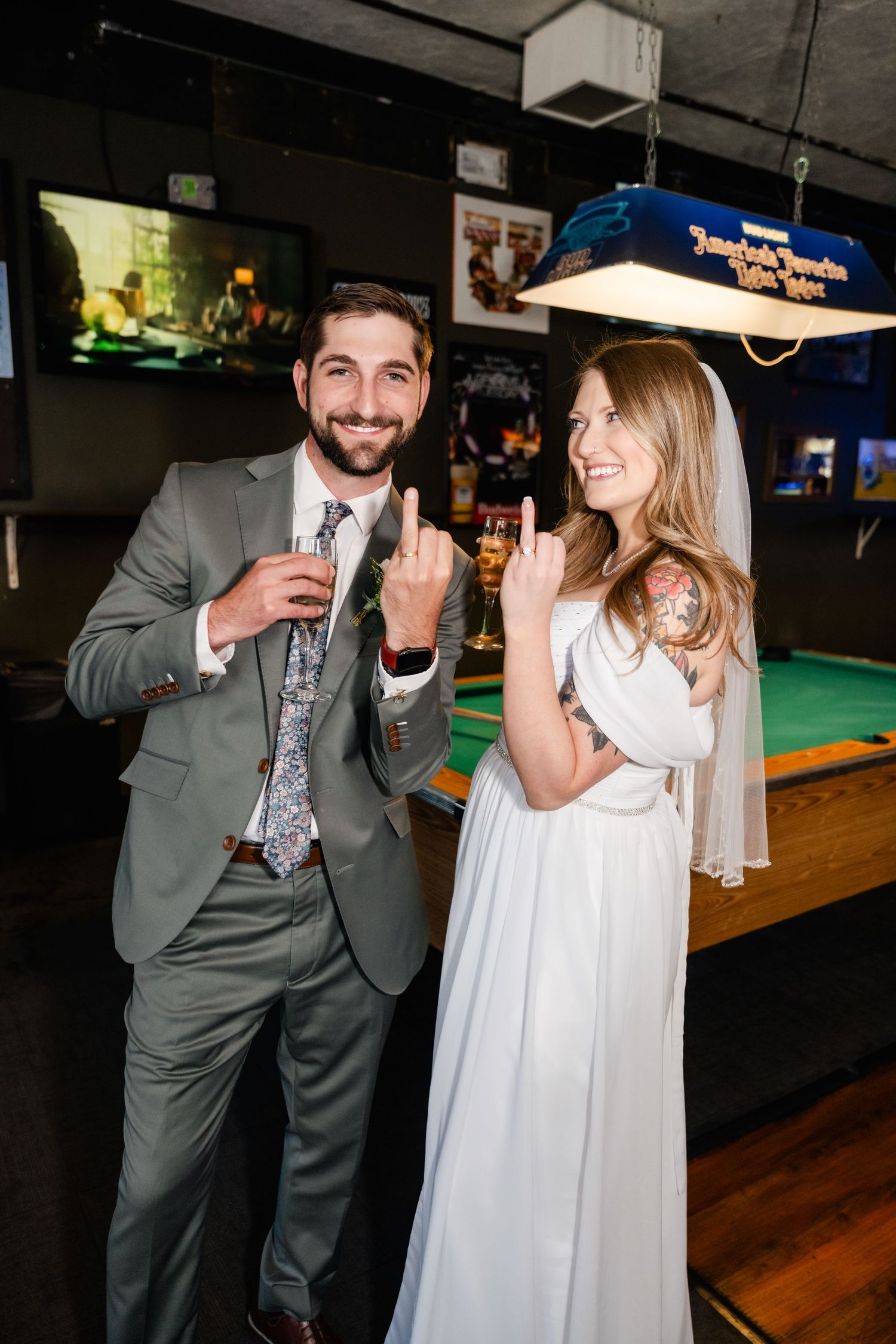 A couple laughs together during their wedding celebration at a bar venue with pool tables.