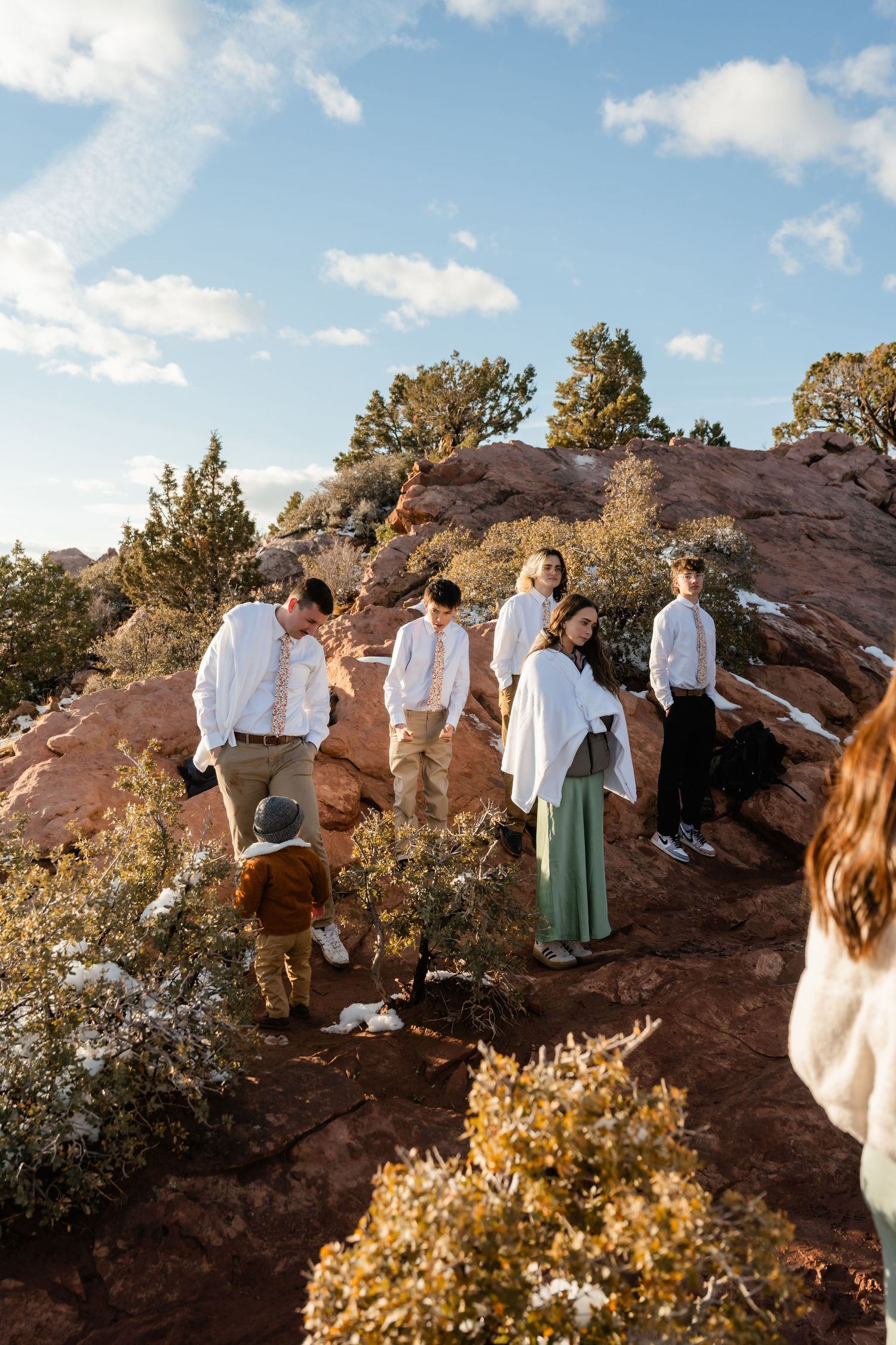 Wedding party gathered on red rock formations during outdoor photo session.