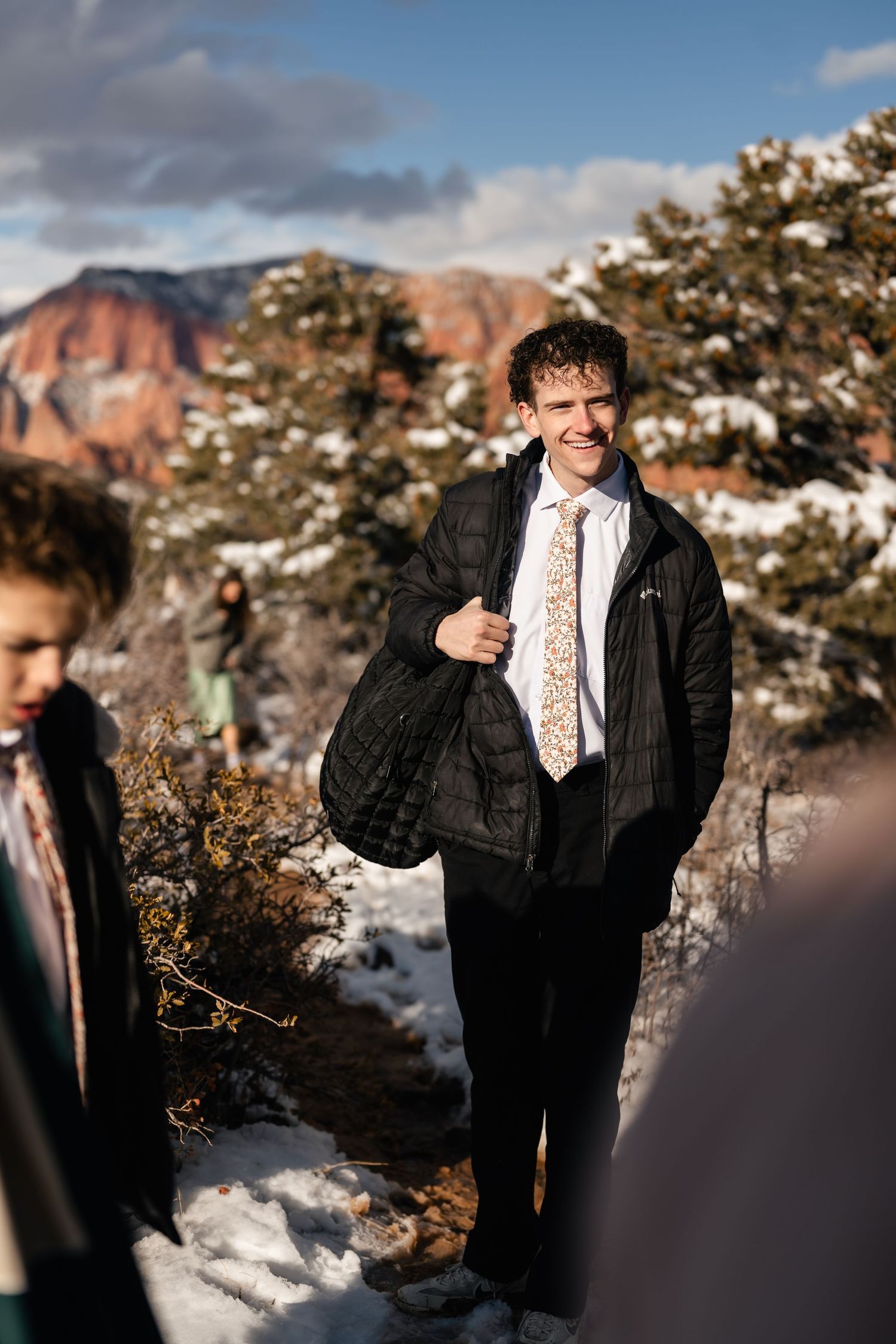 A formal gathering in winter attire against a backdrop of snow-dusted mountains.