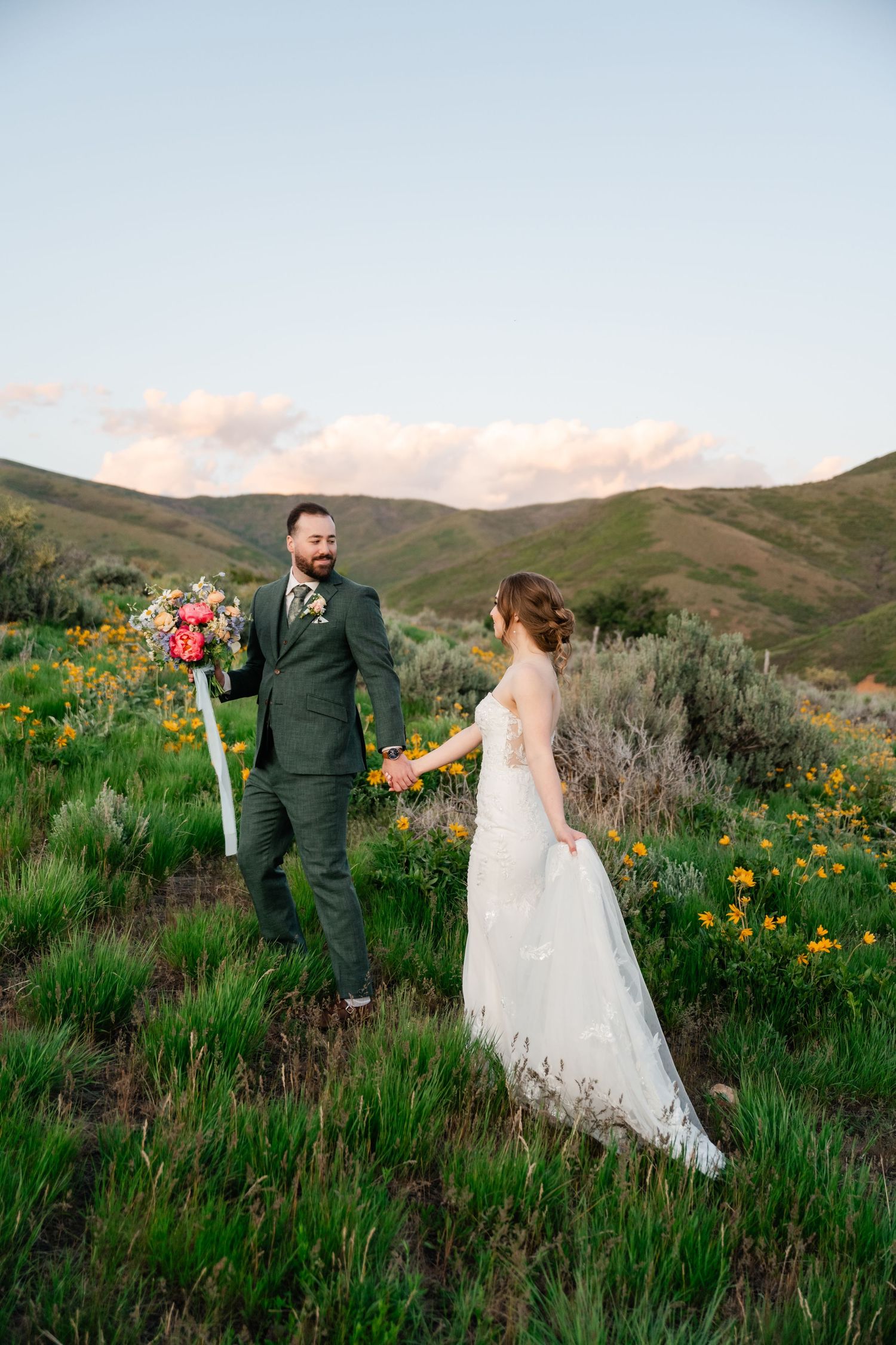 Couple explores wildflower meadow during golden hour mountain wedding photoshoot.