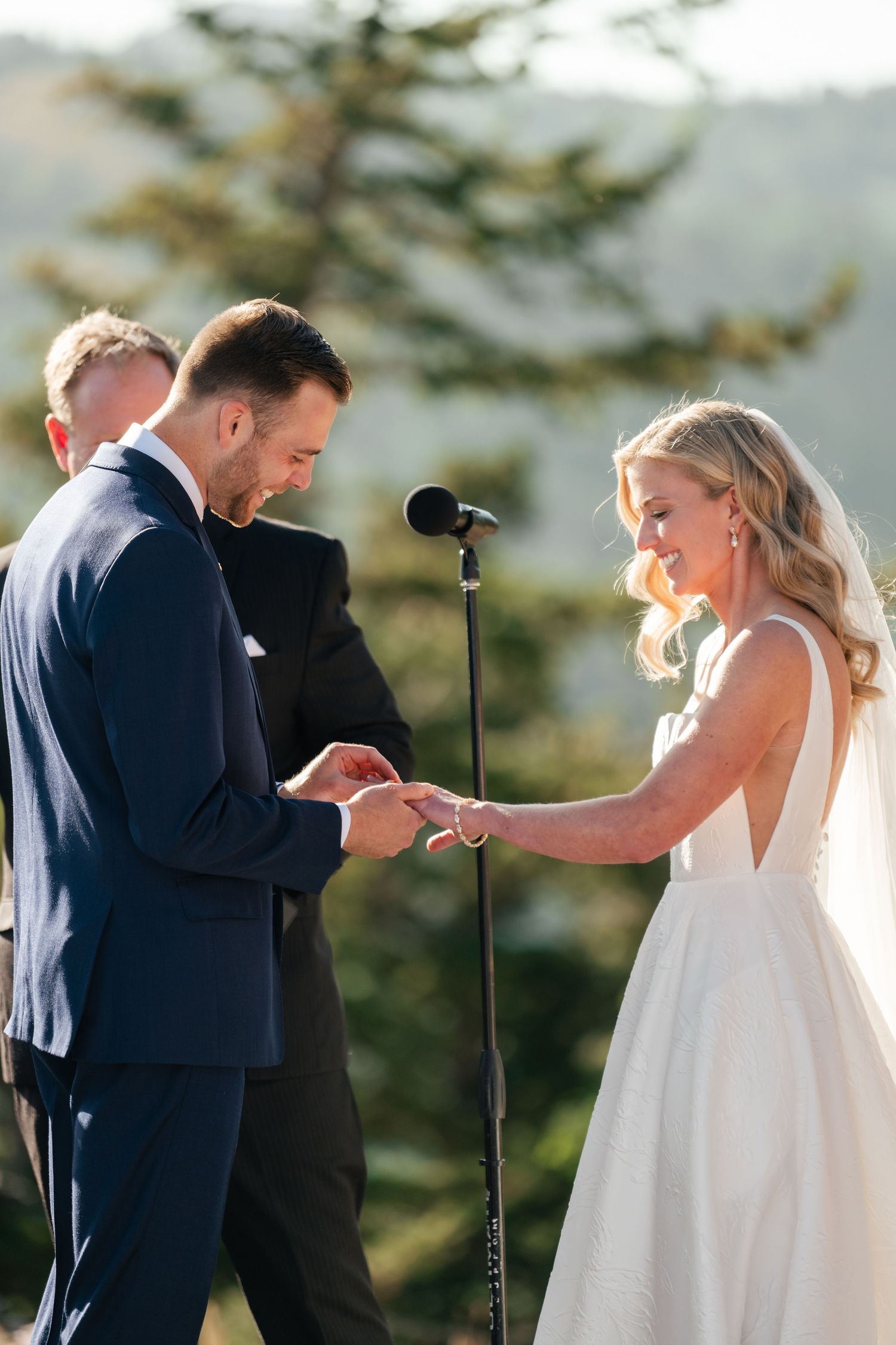 A romantic outdoor mountain wedding ceremony as couple exchanges rings in front of an officiant. Park City Wedding Photographer.