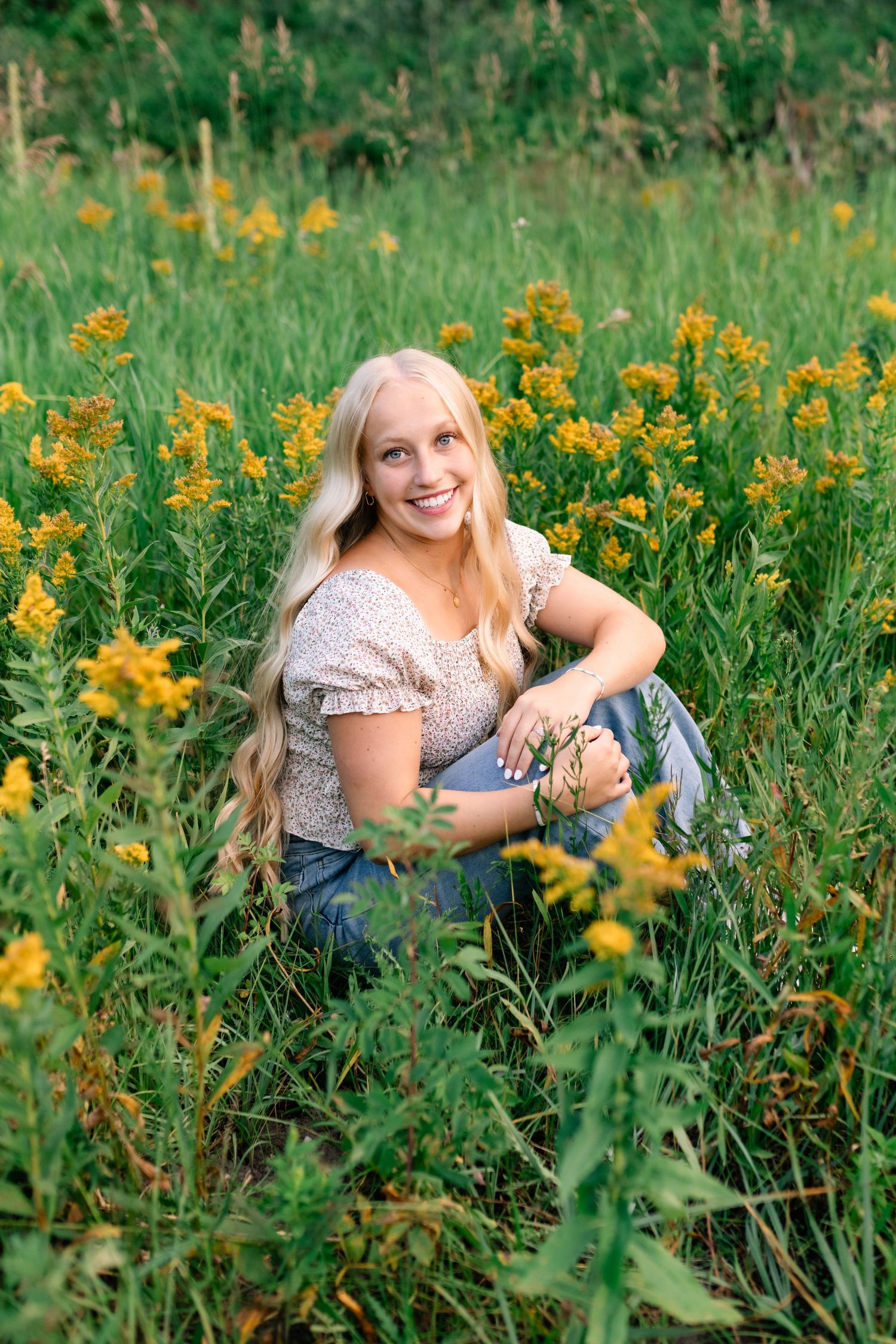 Sitting and smiling portrait in a field of wildflowers by Utah Senior Photographer, Coley Cook