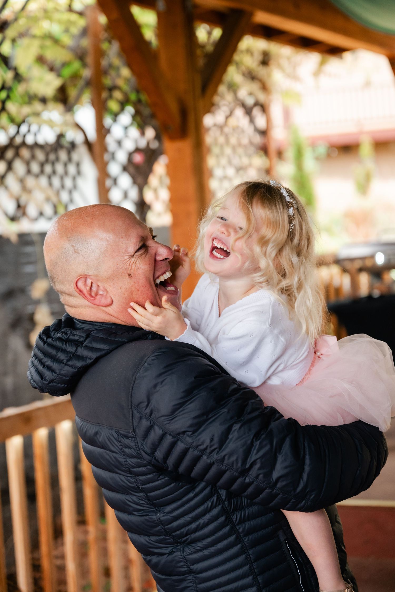 Joyful couple sharing an intimate moment on a wooden deck with string lights overhead.
