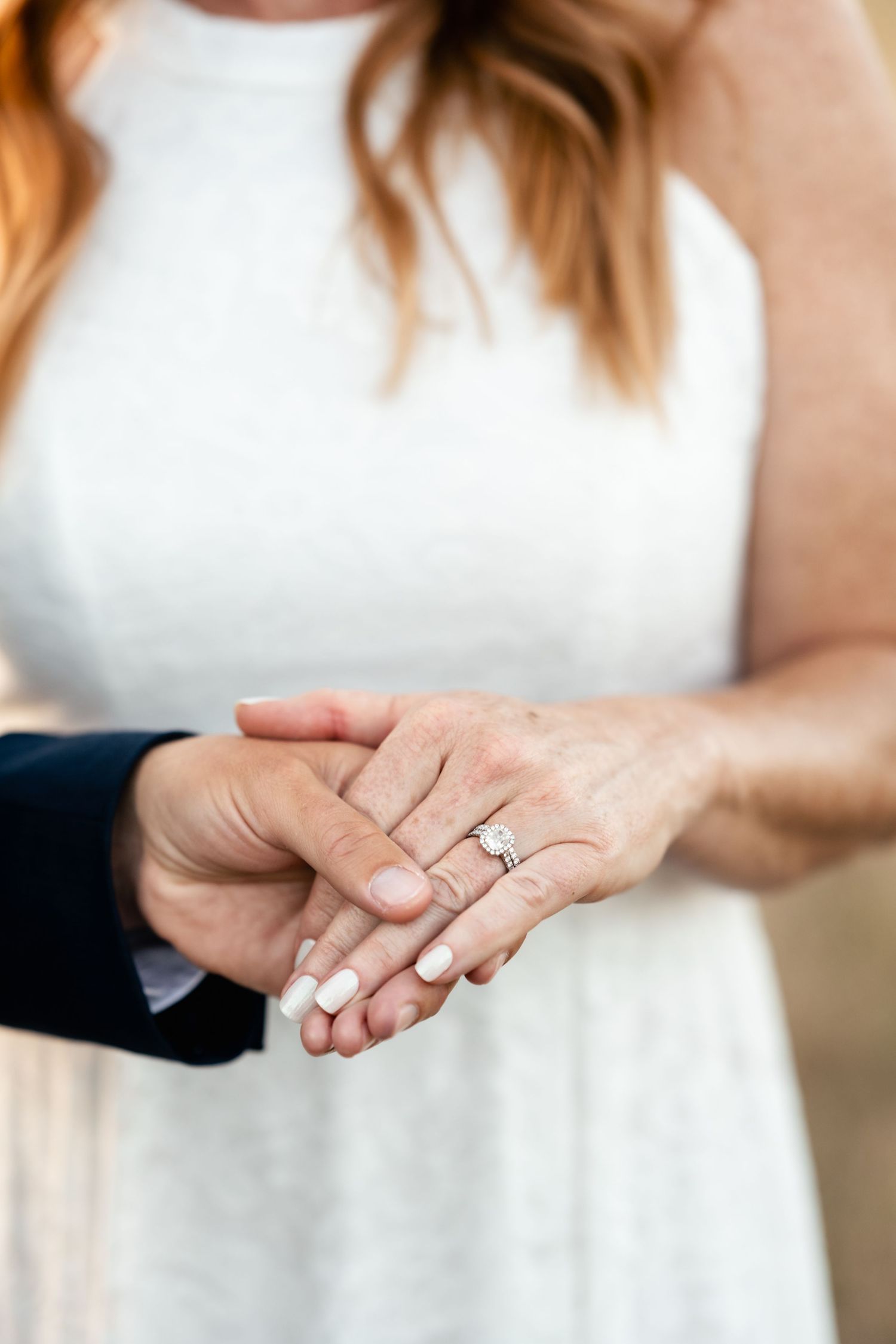 Close-up of hands showing elegant wedding rings and manicured nails.