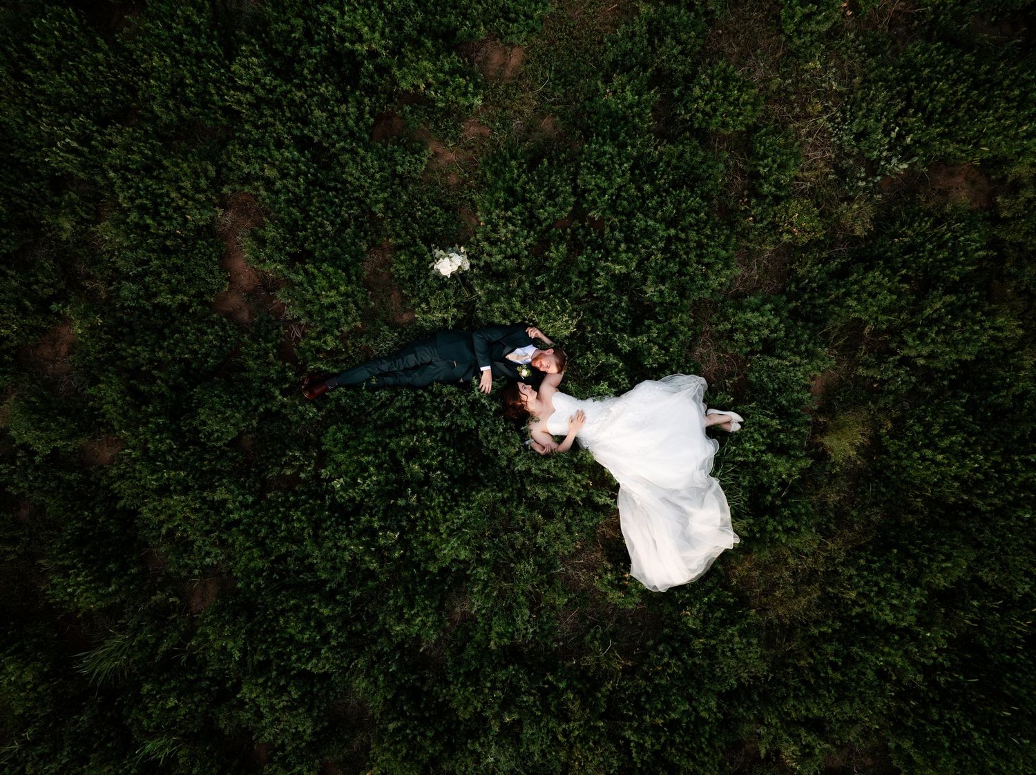 A series of aerial drone shots showing a couple in wedding attire walking through a lush green garden setting.