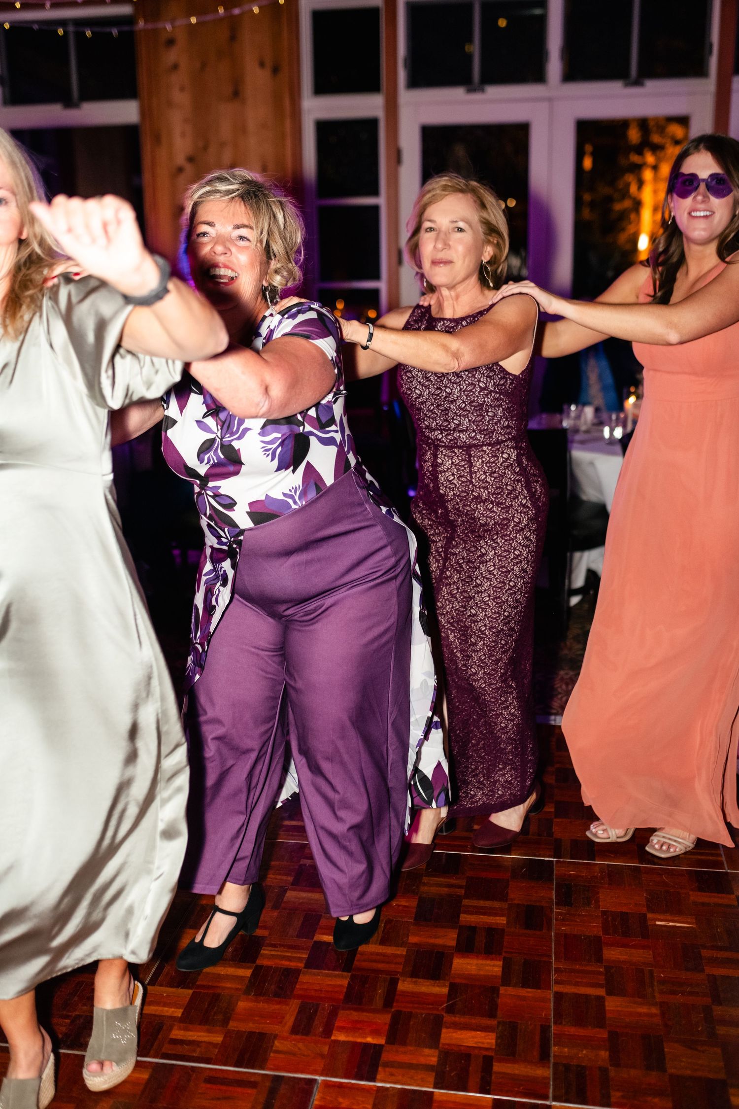 Wedding reception guests dancing enthusiastically on a parquet dance floor.