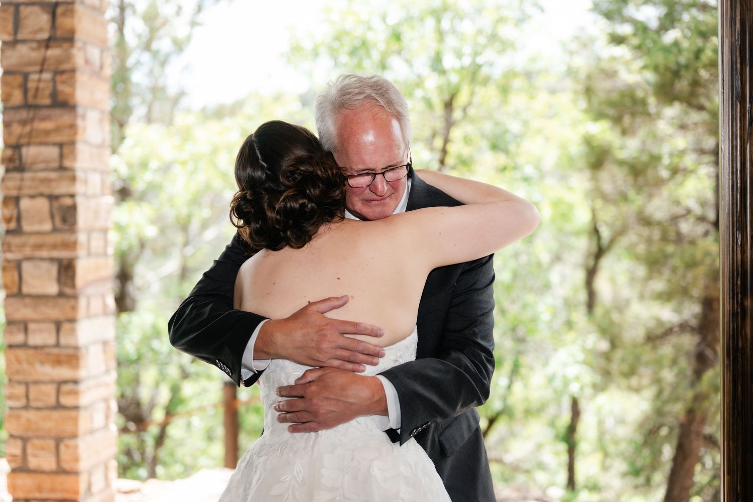 Emotional embrace between wedding couple during outdoor ceremony.