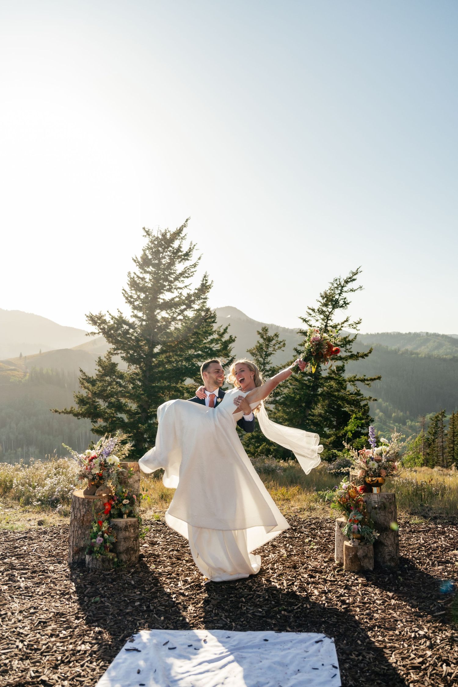 Couple performs a joyful dance sequence against a backdrop of mountain peaks and evergreen forest.