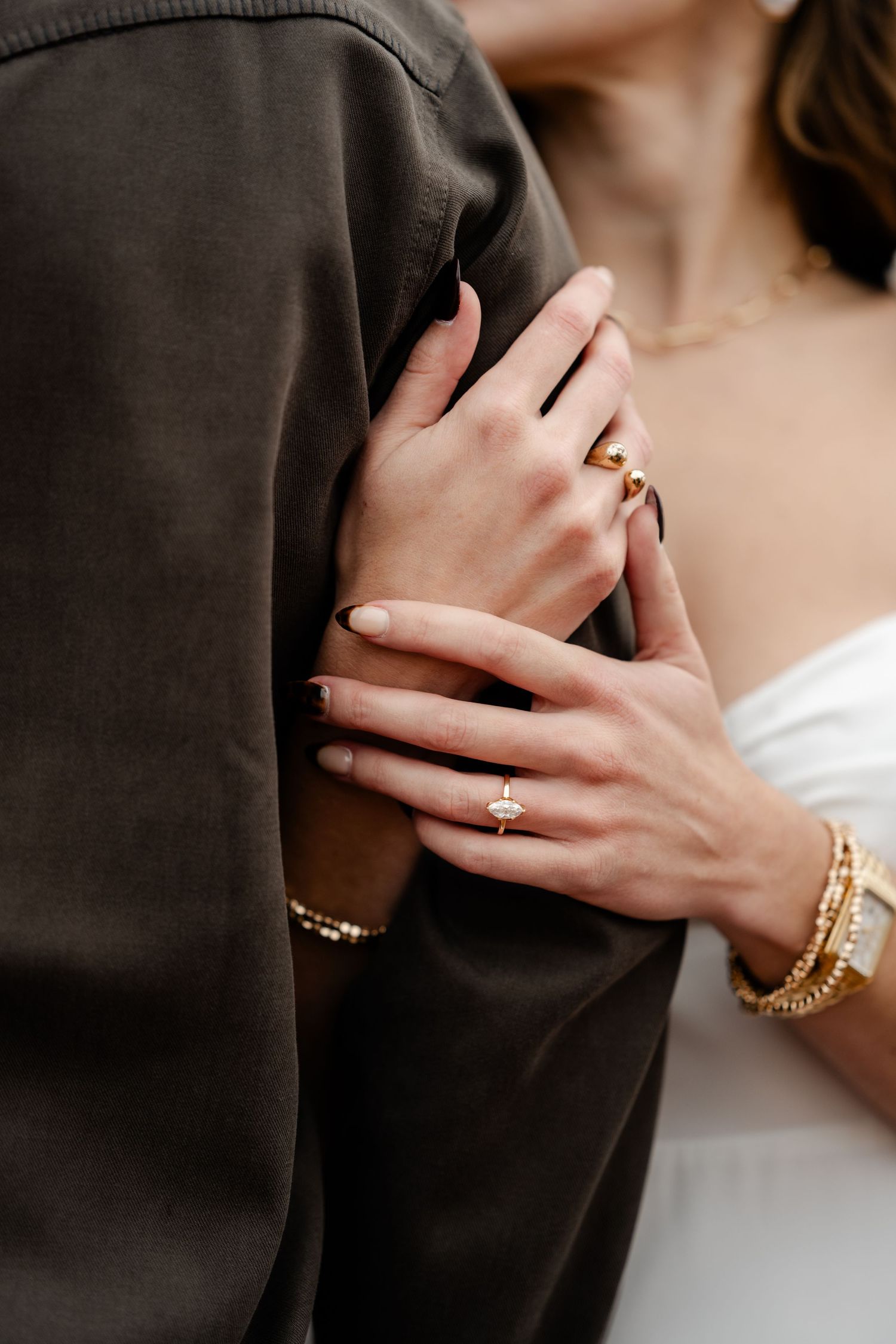 Close-up details of hands with jewelry against formal attire.