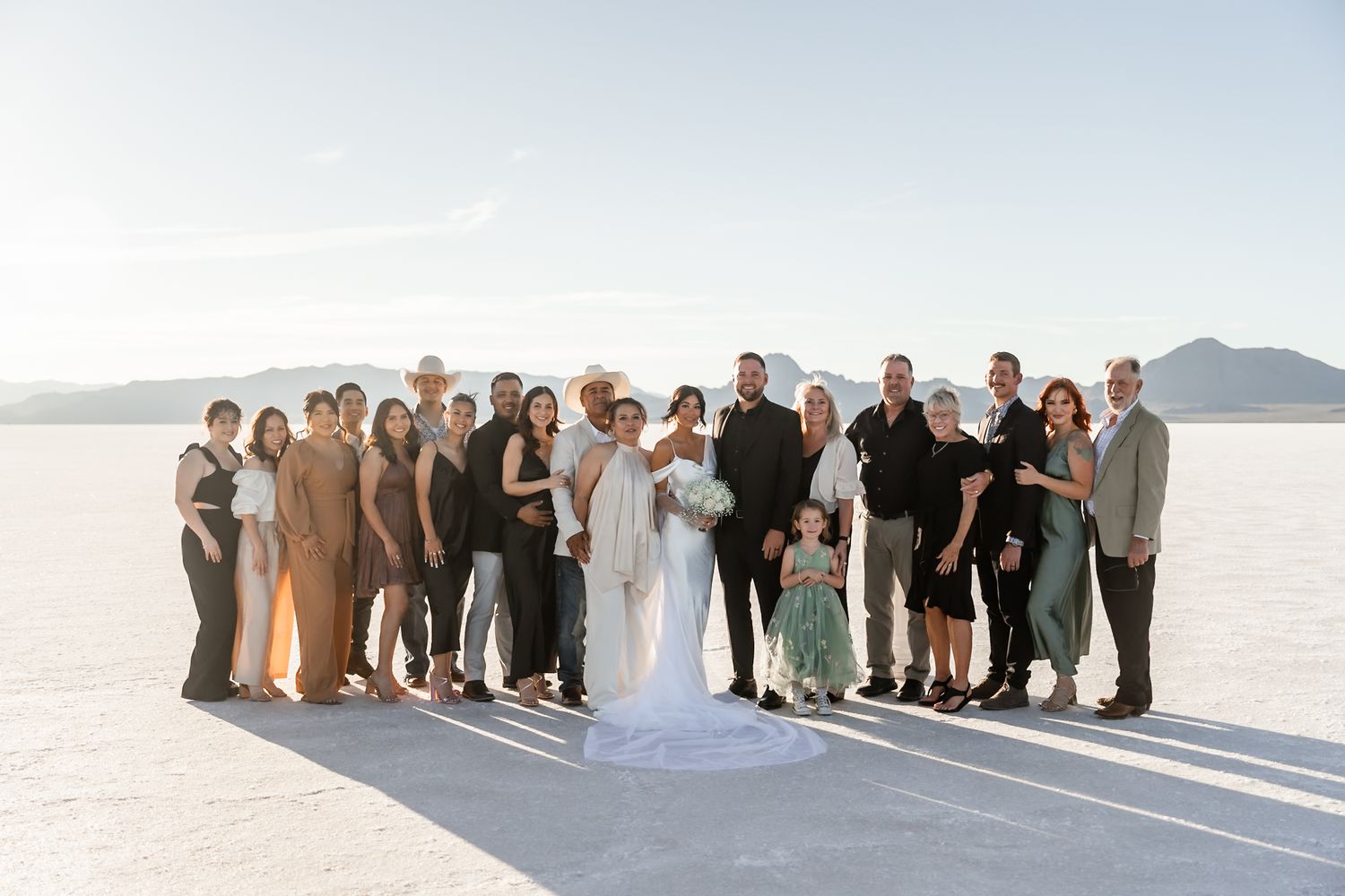 Wedding party group photo on salt flats with mountains in background.