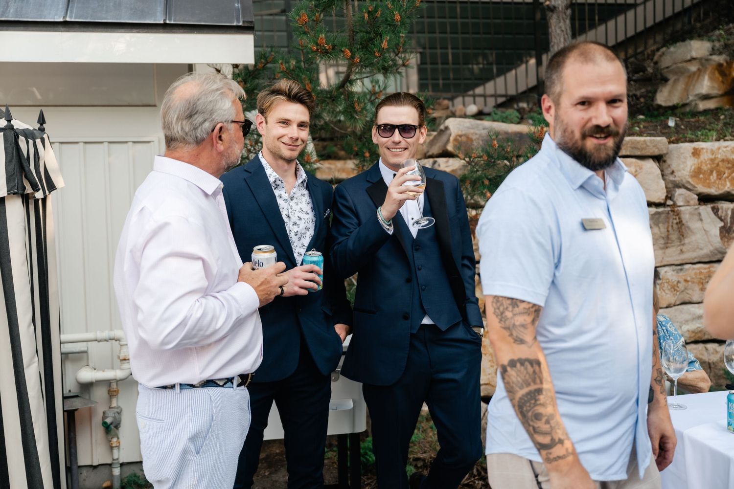Guests at an elegant wedding reception share laughter and conversation in an outdoor venue setting.