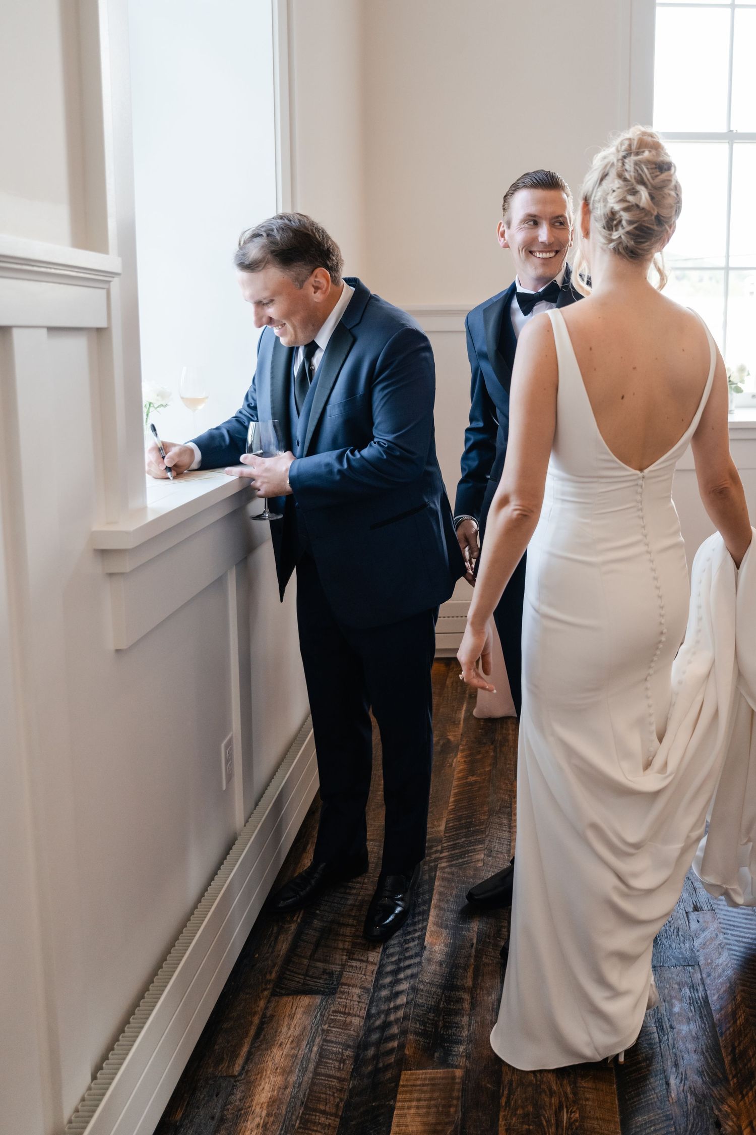 Candid wedding moment captured in a bright white room with elegant decor.