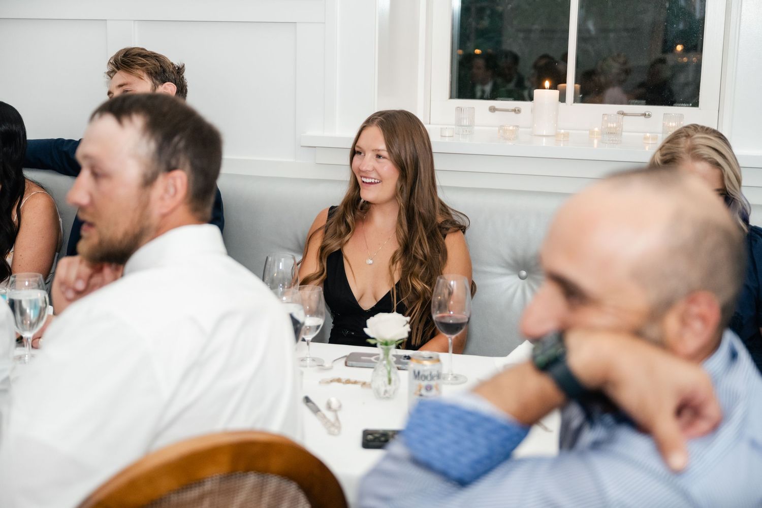 Wedding guests engaged in lively conversation around white-clothed dining tables.