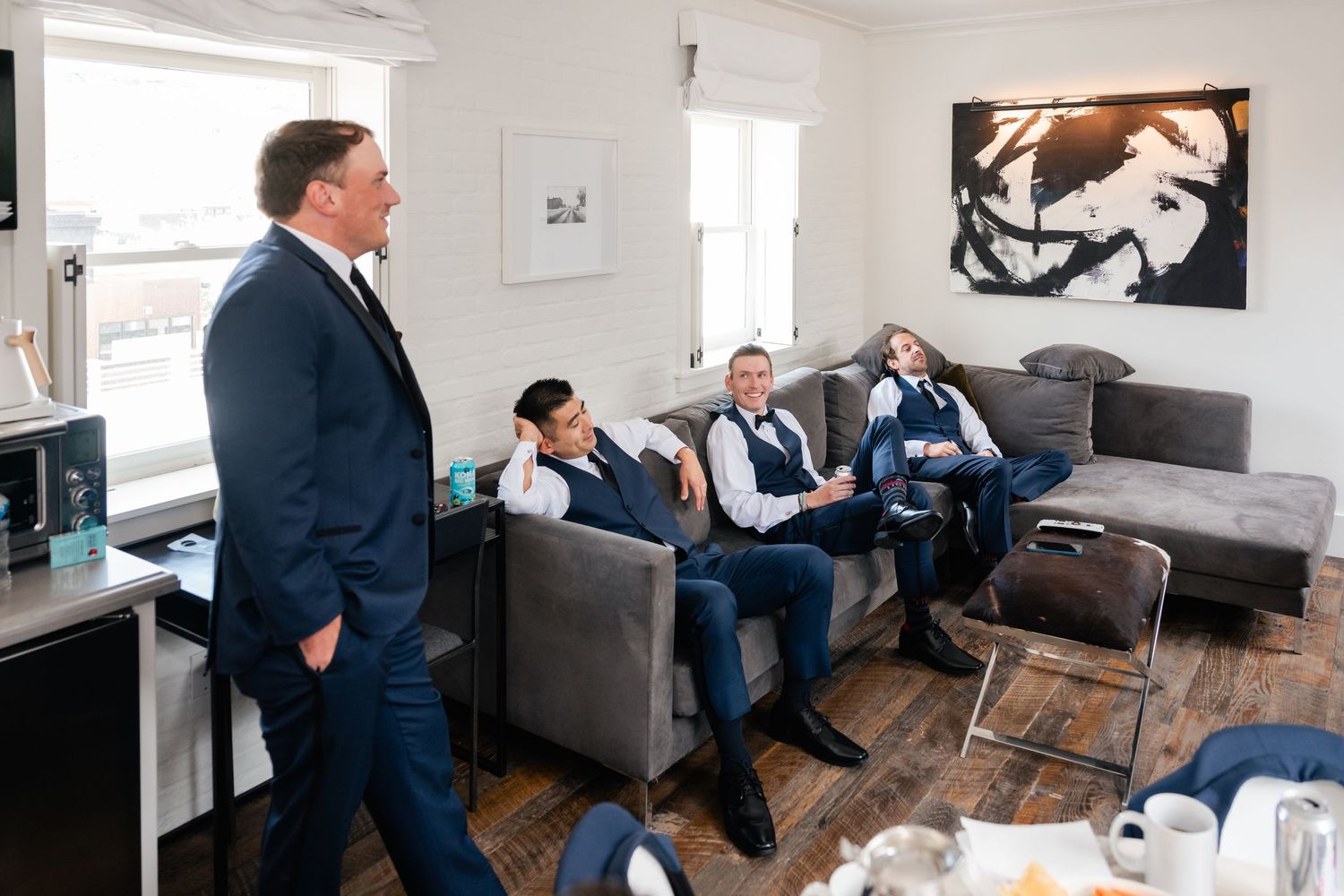 Wedding party relaxing in a modern room with white walls and hardwood floors.
