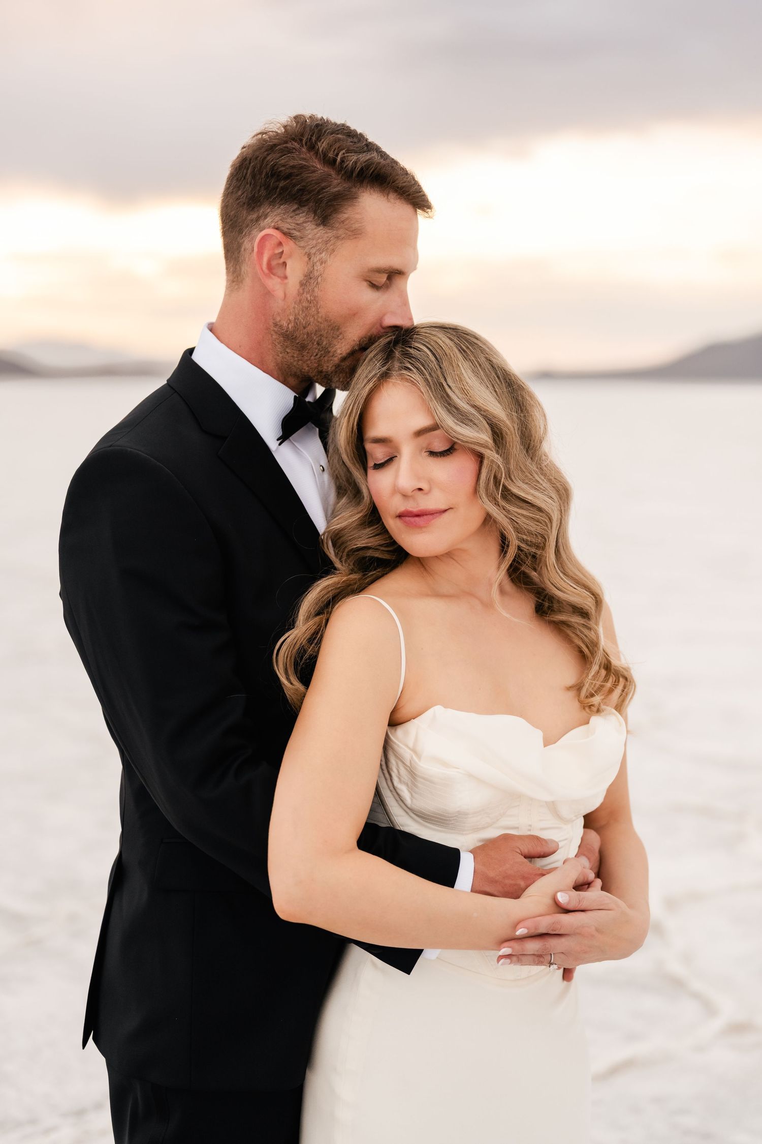 Salt Flats Elopement Photographer. Romantic wedding couple embracing on salt flats during golden hour photoshoot.