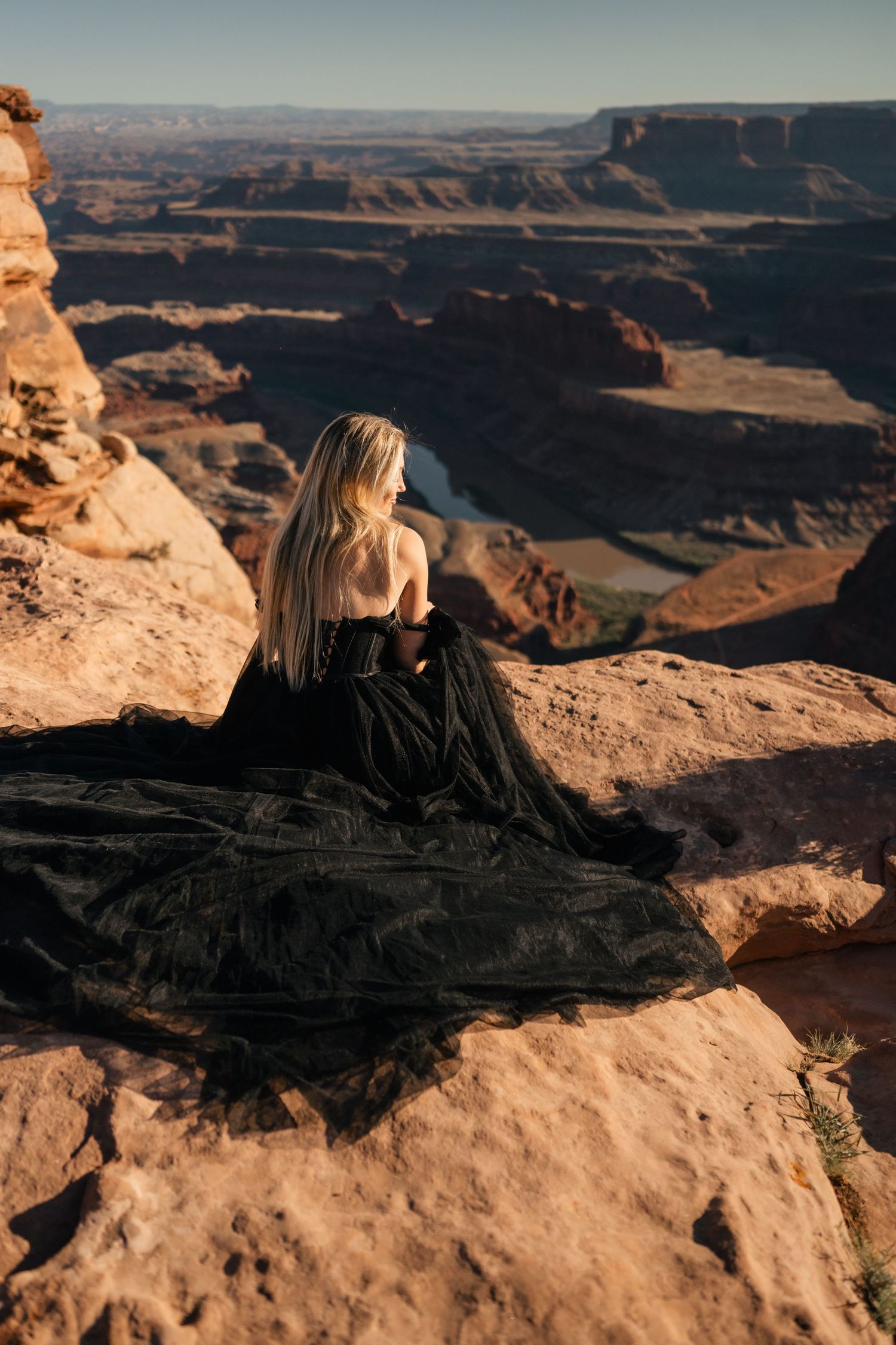 A scenic view of Dead Horse Point State Park in Utah with a person admiring the vast canyon landscape at sunset.