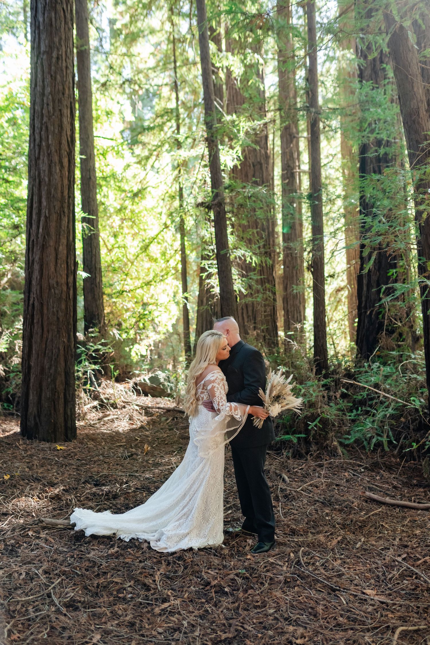 A romantic wedding photoshoot among towering redwood trees in a forest setting.