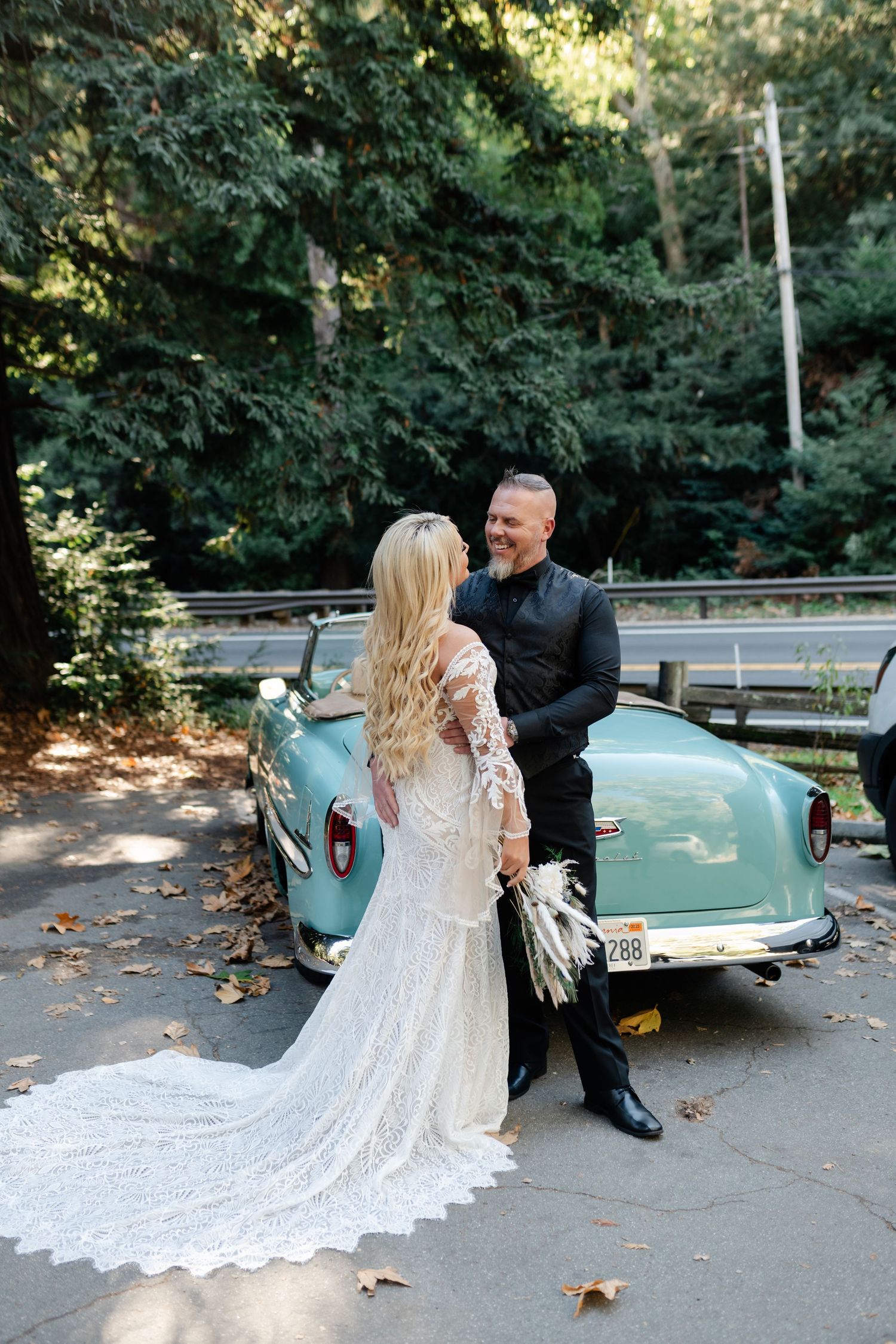 A romantic wedding photo series with a vintage turquoise car featuring a lace dress train trailing on the ground.