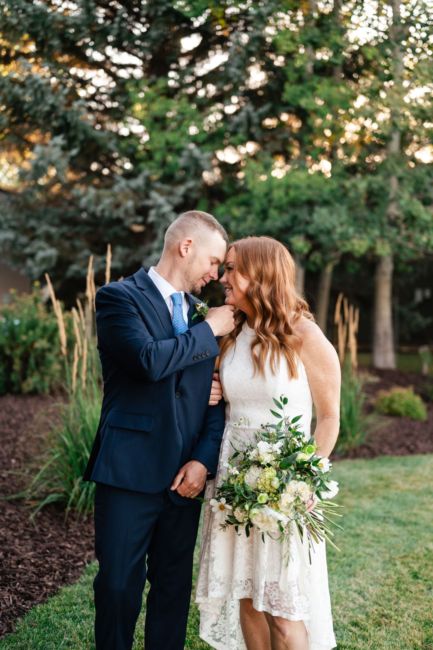 A romantic moment captured between a couple in formal attire against a natural backdrop.