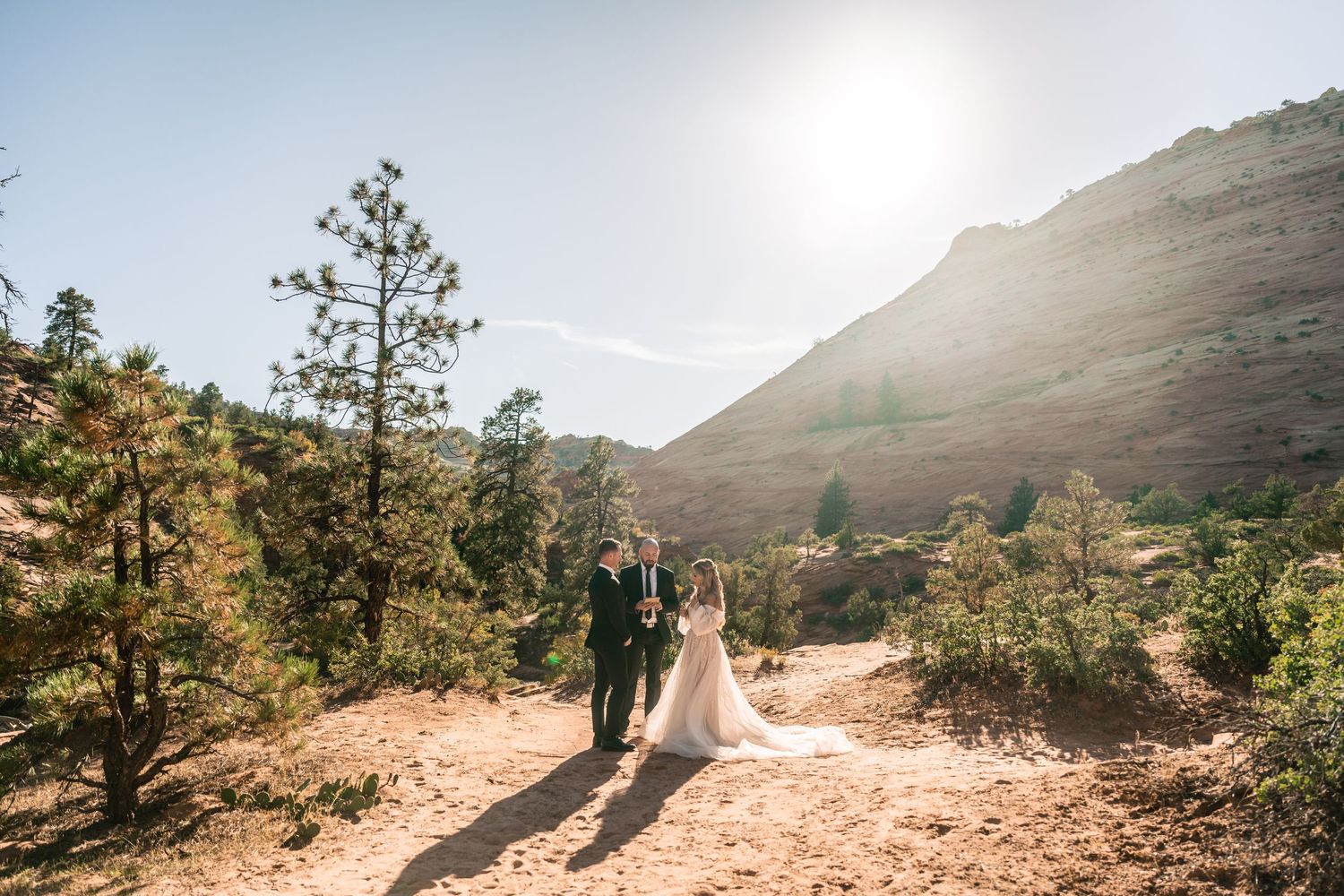 A wedding ceremony silhouetted against mountain slopes during golden hour.