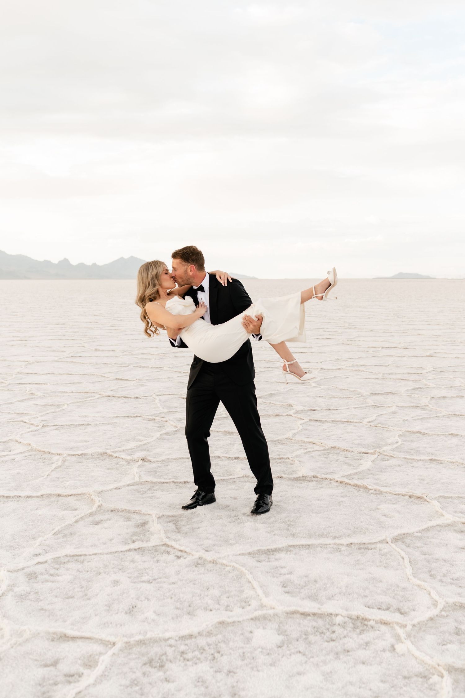 Salt Flats Elopement Photographer. A couple dances together on the white salt flats at sunset, creating a romantic and ethereal scene.
