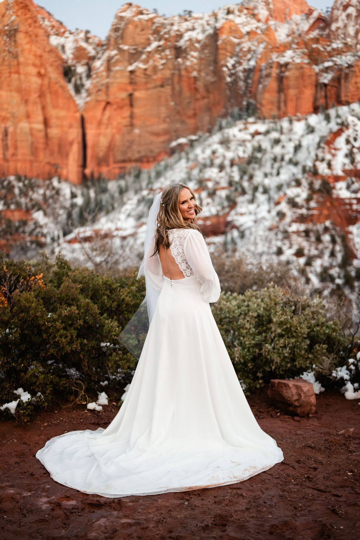 Bridal portraits with flowing white dress against snow-dusted red rock canyon backdrop.