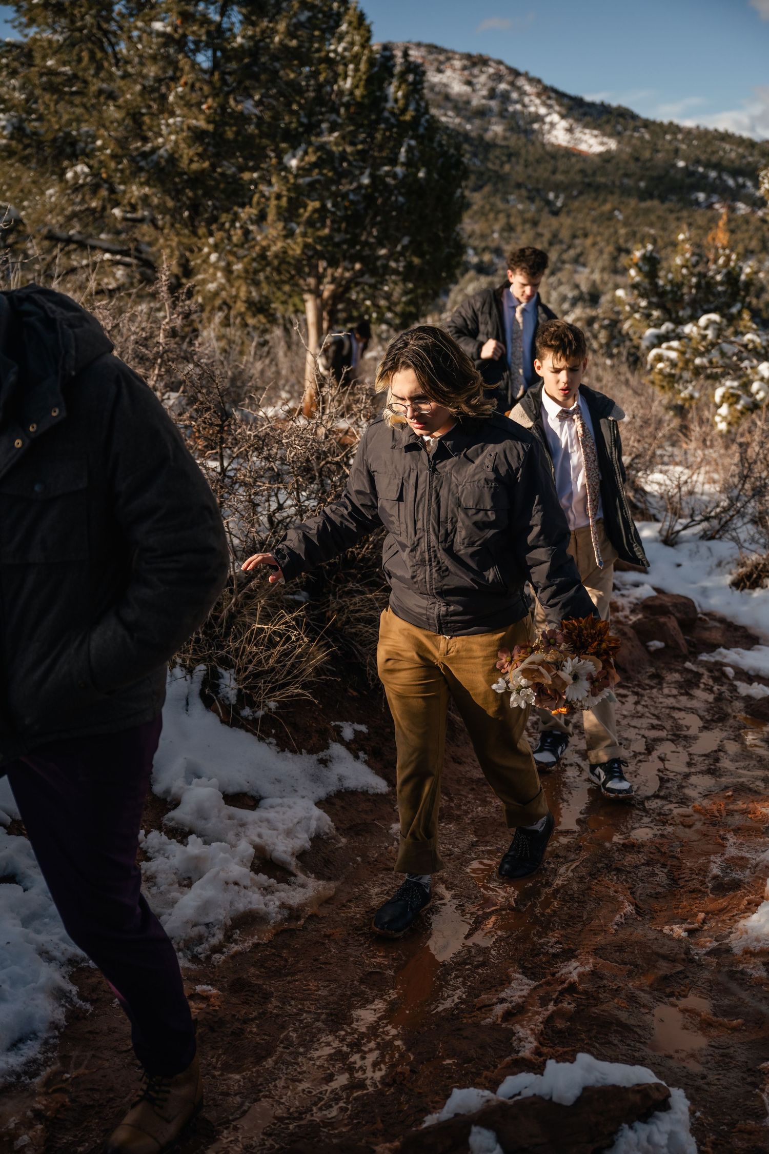 Wedding party walking through snowy terrain with desert mountains in the background.