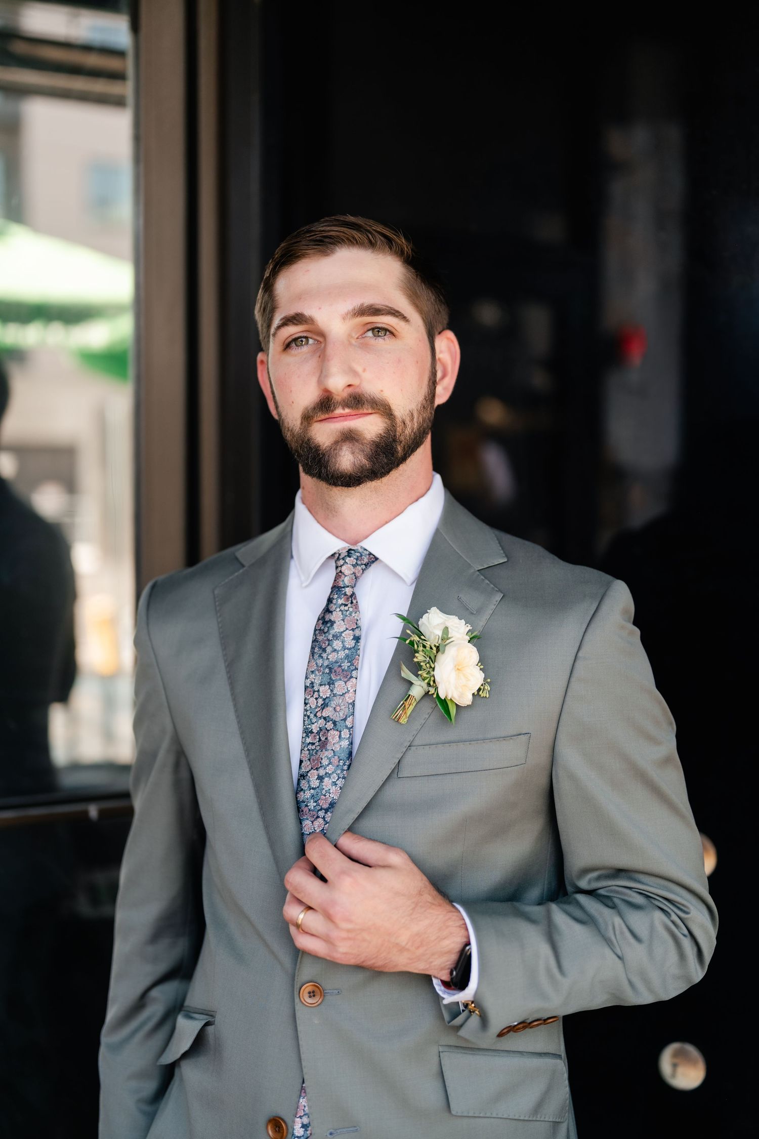 Wedding party member in gray suit with floral tie and boutonniere poses in a series of candid shots.