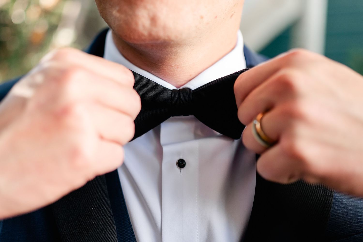 Close-up sequence showing hands adjusting a black bow tie on a white dress shirt collar.