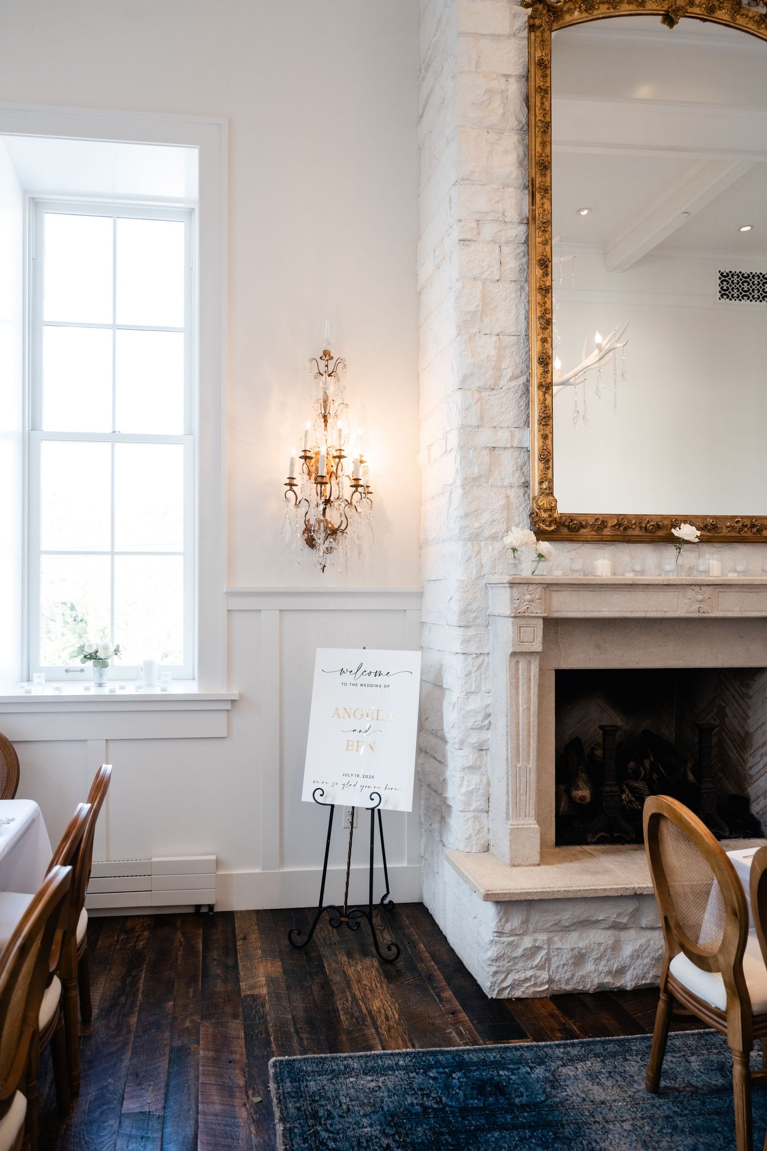 A refined dining space with white walls, dark wood floors, and a gold-framed mirror.
