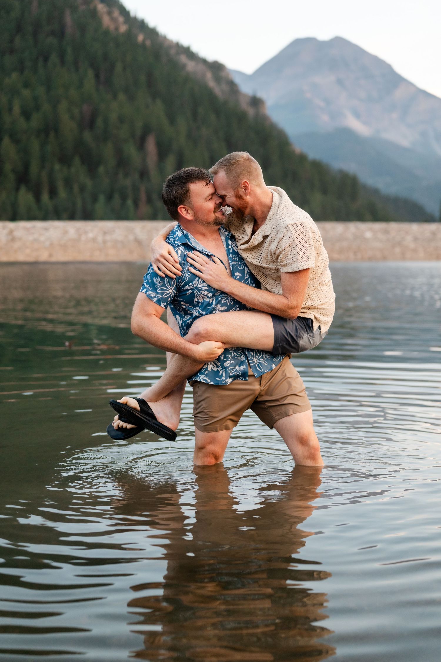 Couple having a water fight at Tibble Fork Reservoir. Two men embracing and kissing while standing in a scenic mountain lake.