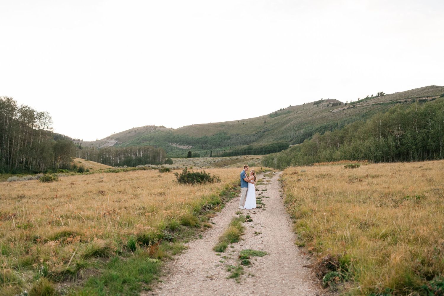 Romantic Guardsman Pass location for surprise proposal. Couple walking on a path through golden meadows with green hills and aspen trees.