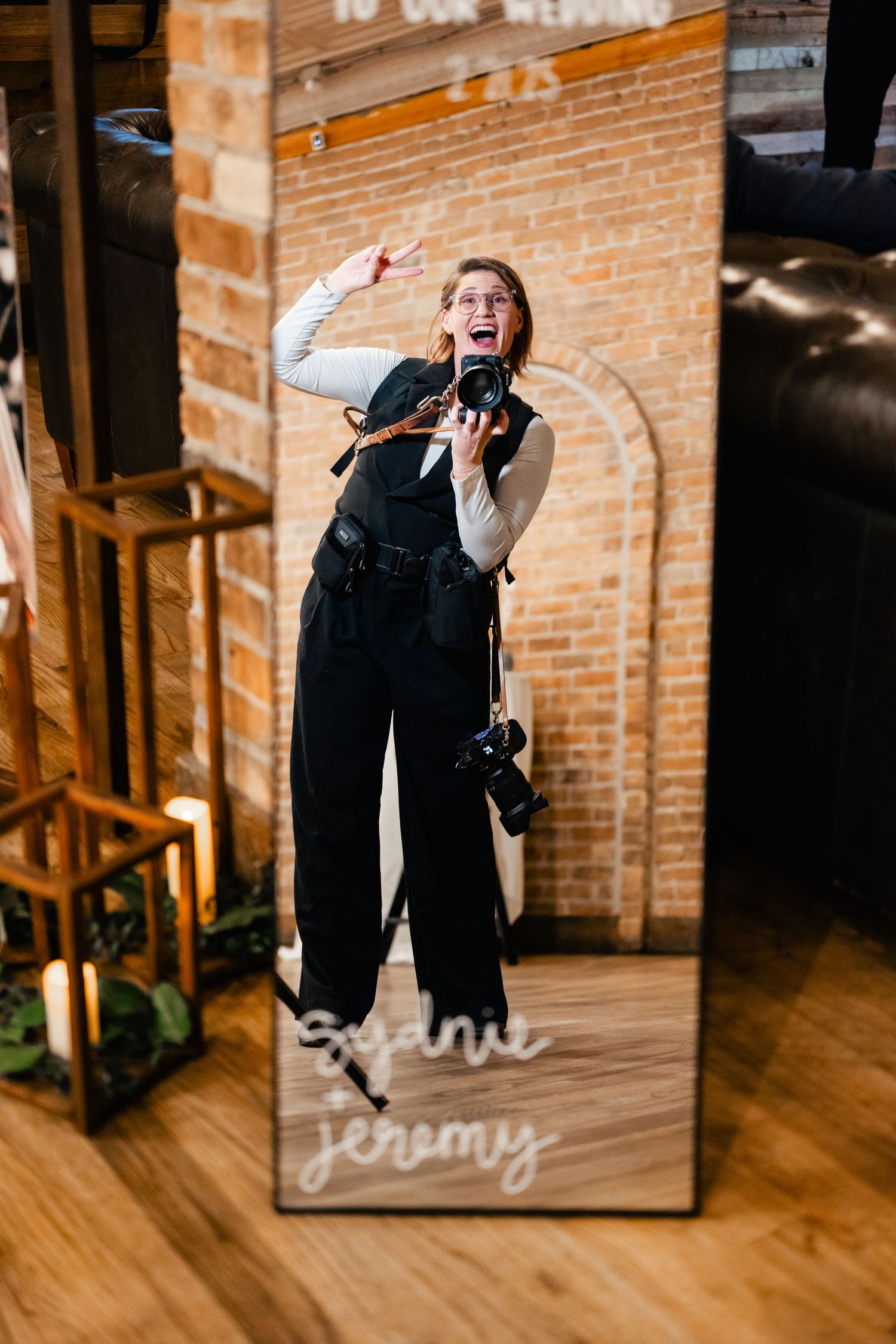 A candid moment captured in a mirror reflection at an indoor venue with exposed brick walls.