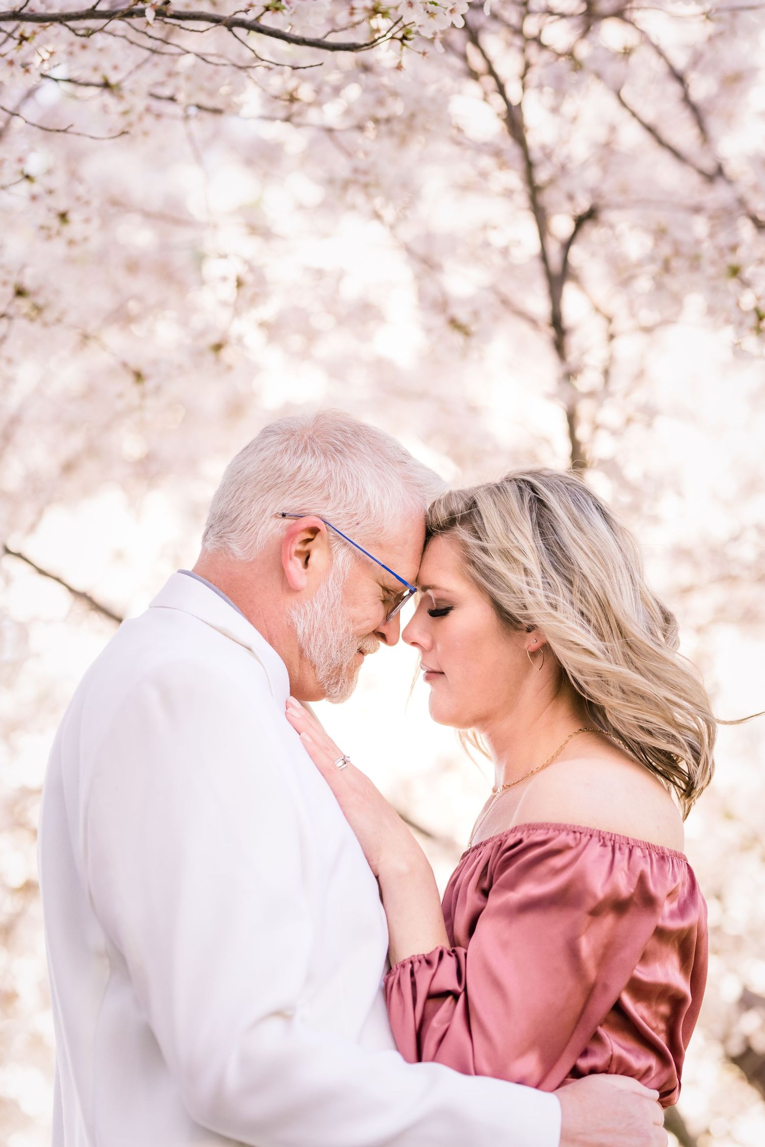 Engaged couple forehead to forehead under the blossoms at the Utah State Capitol by Utah Wedding photographer Coley Cook