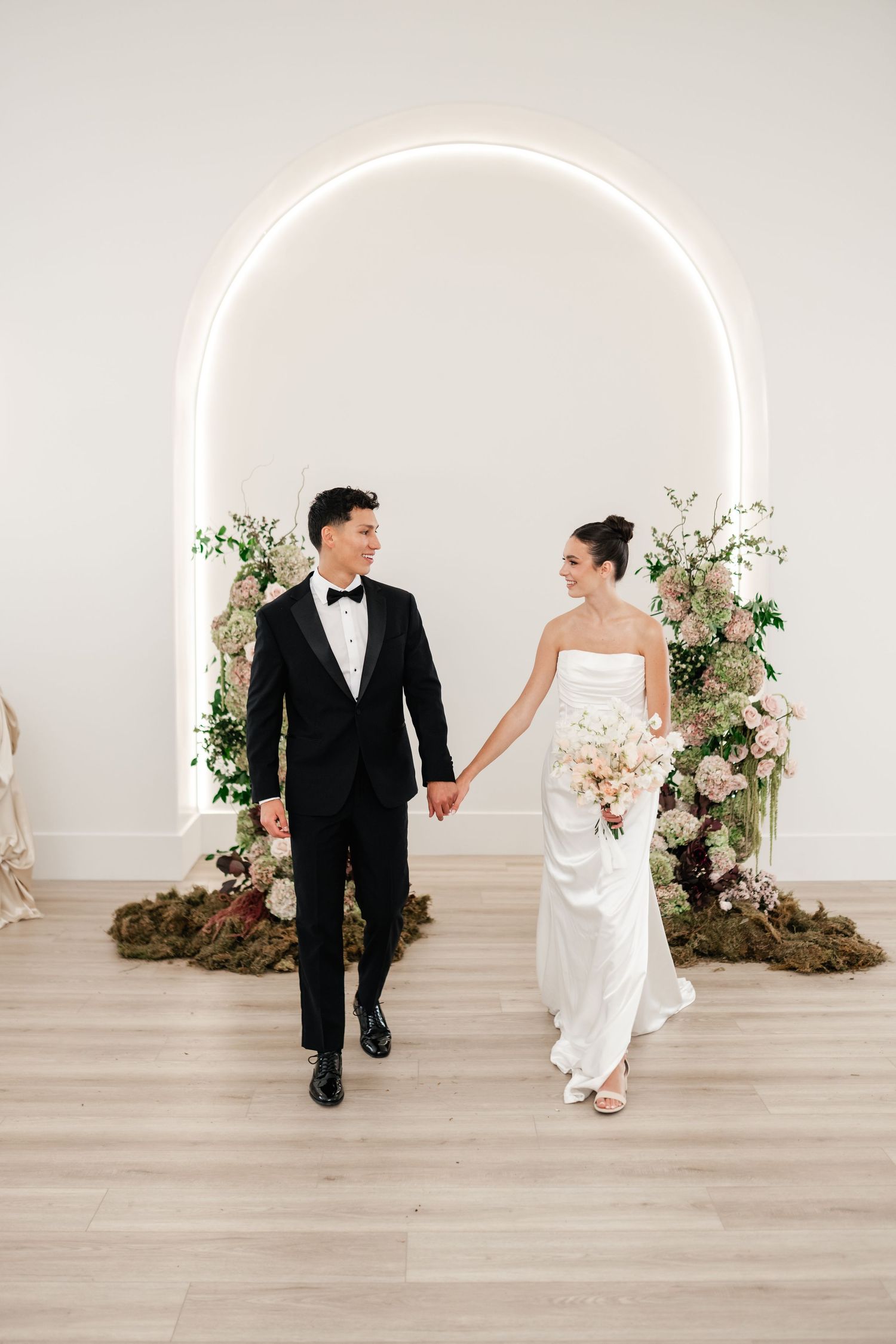 Playful wedding photo showing a couple interacting against a white archway with floral arch. Best Utah Wedding Photographer. Utah Weddings.