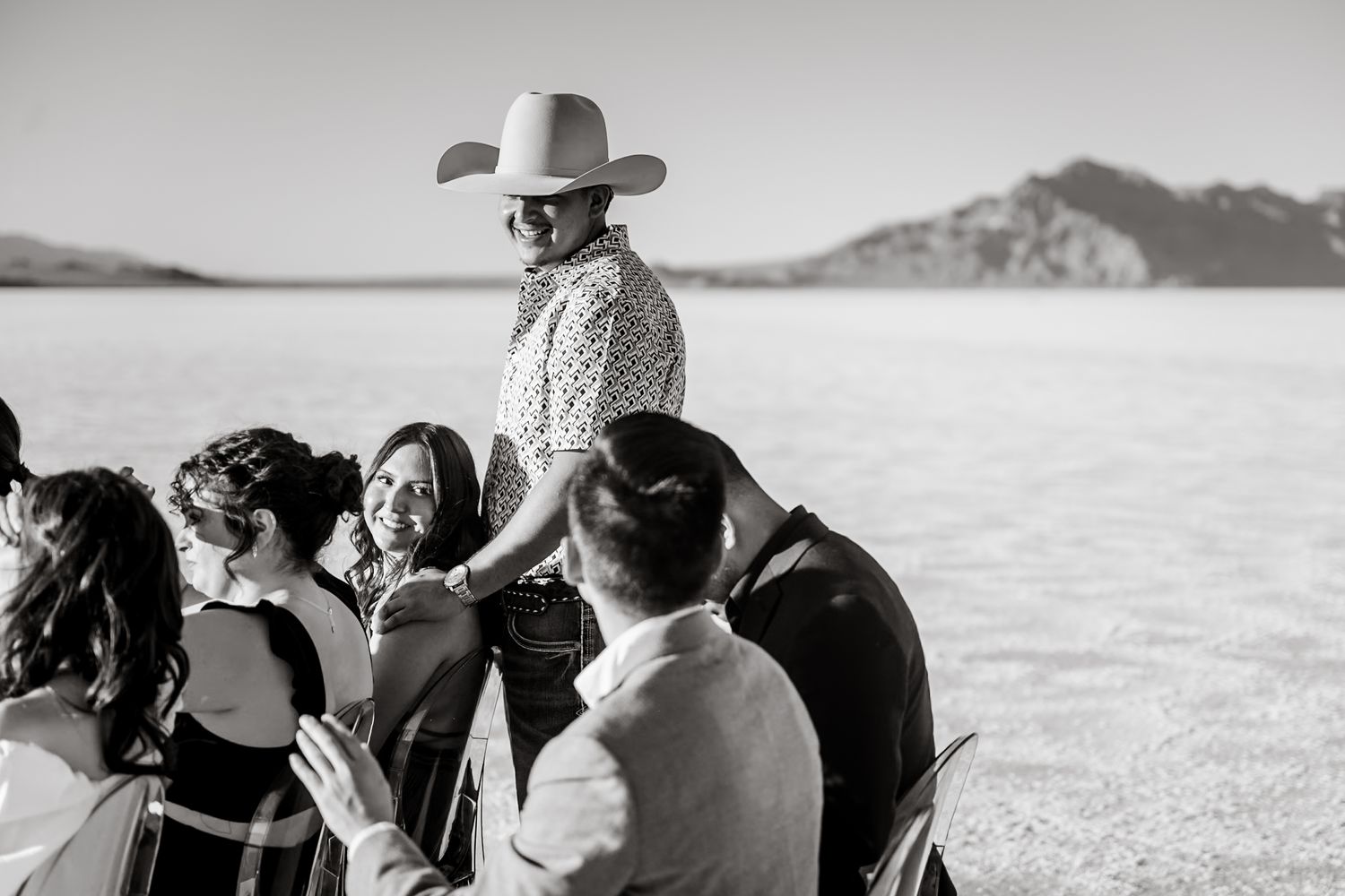 Black and white candid shots of wedding guests watching ceremony on salt flats.