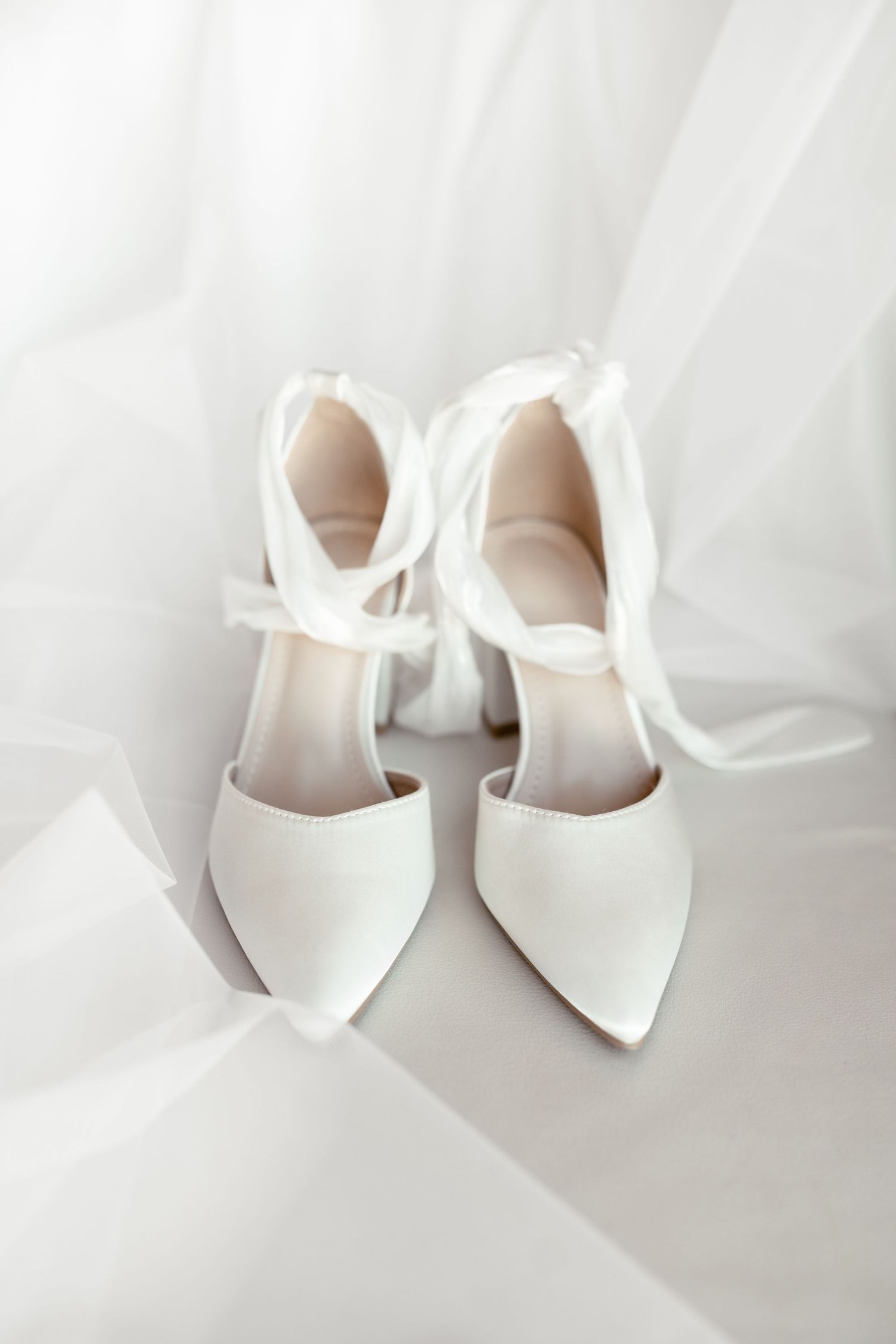 White wedding shoes with delicate bow details against a light background.
