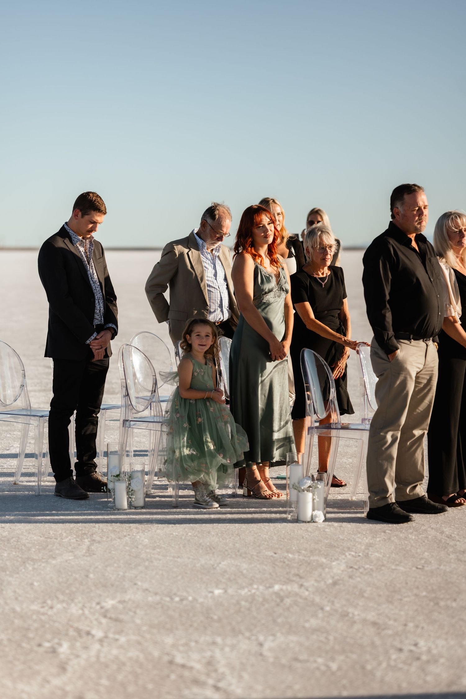 Wedding guests lined up on white chairs against a stunning salt flat landscape.