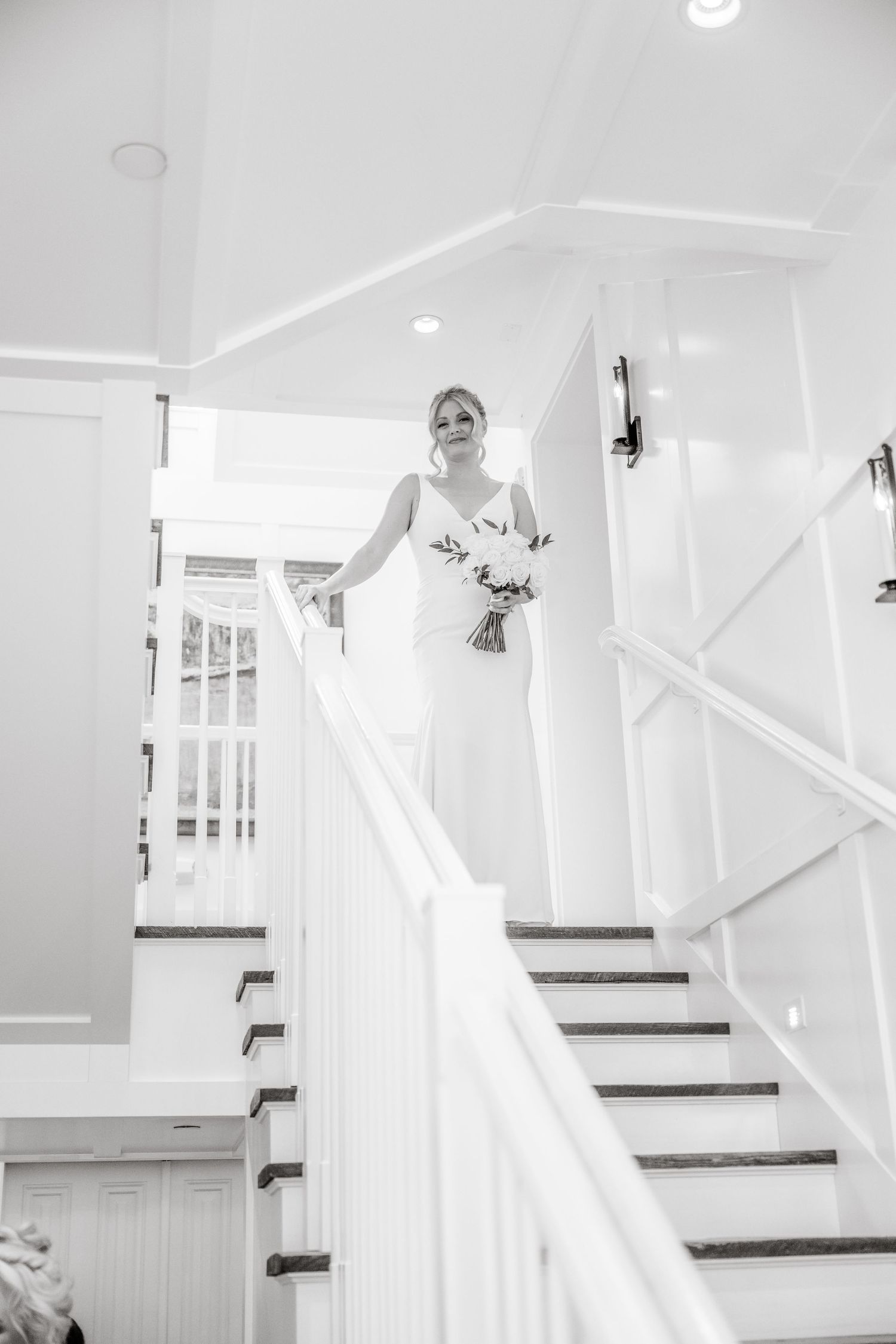 A bride in white gown descending elegant white stairs in sequence of photos.