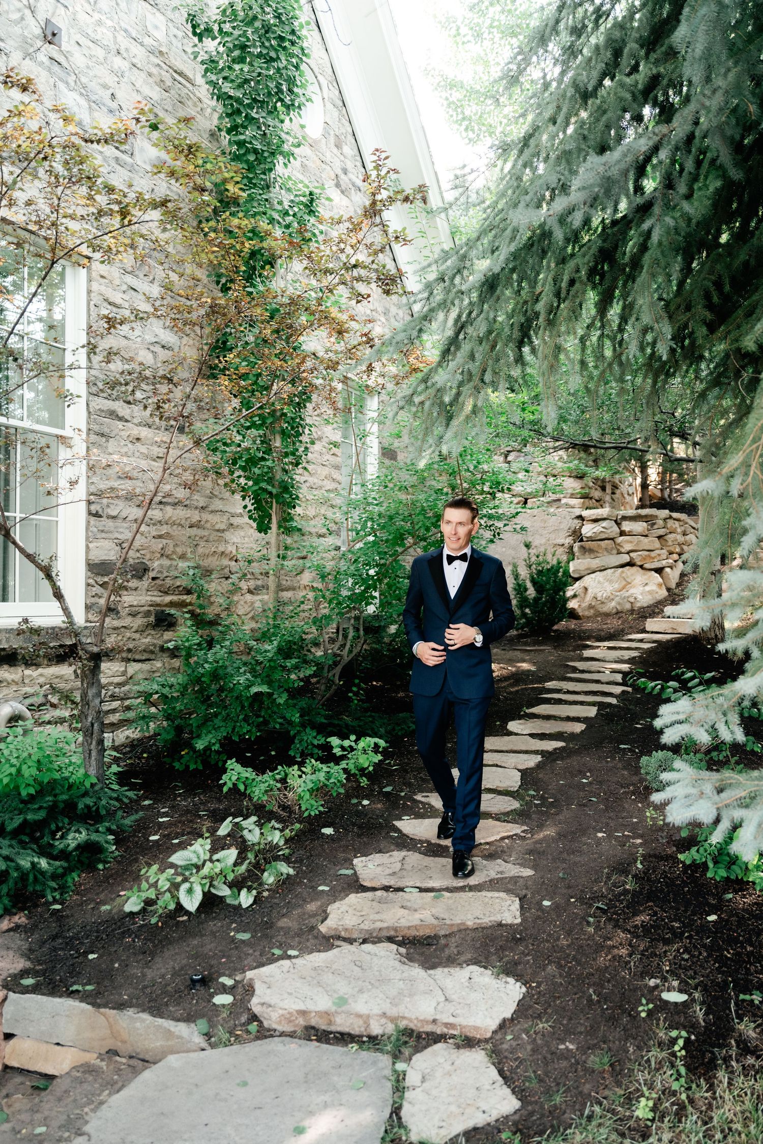 Stone steps wind through a lush garden setting with evergreen trees and natural landscaping.