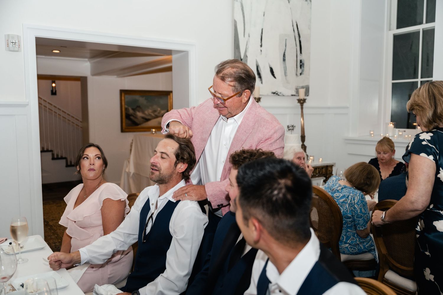 Wedding reception guests mingling and socializing in elegant white room.