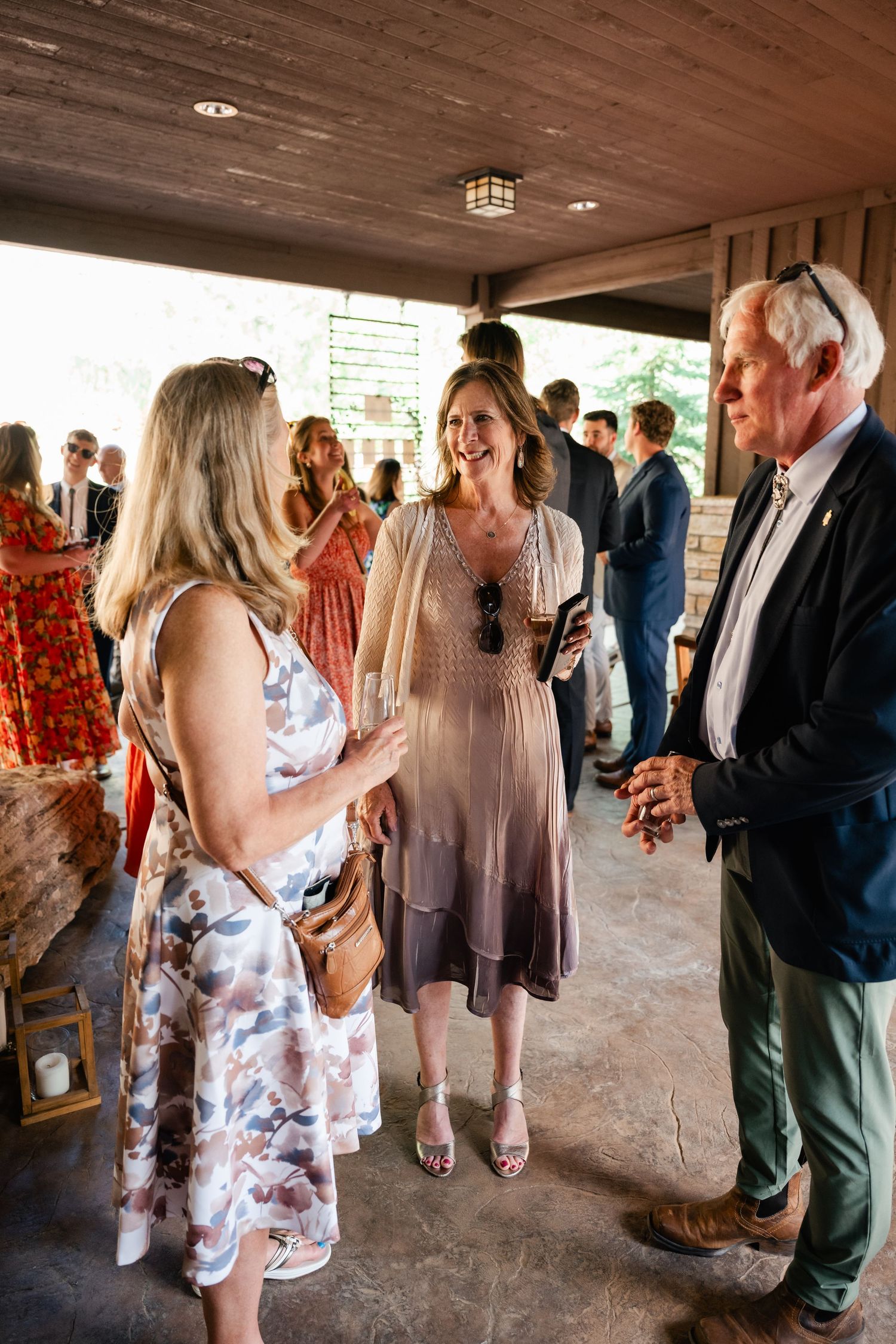 Wedding guests mingling in a covered outdoor reception area during a celebration.