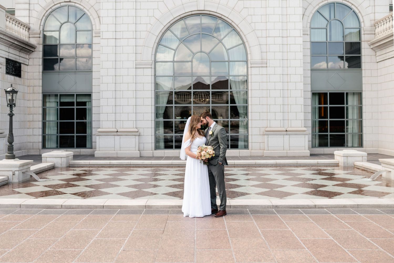 A series of five romantic wedding photos showing a couple in white against a grand stone building with arched windows.